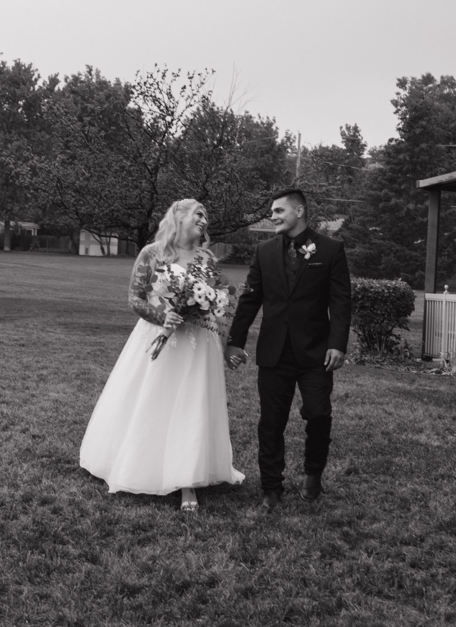 Black and white wedding photography showing outdoor celebration moments on a grassy field.