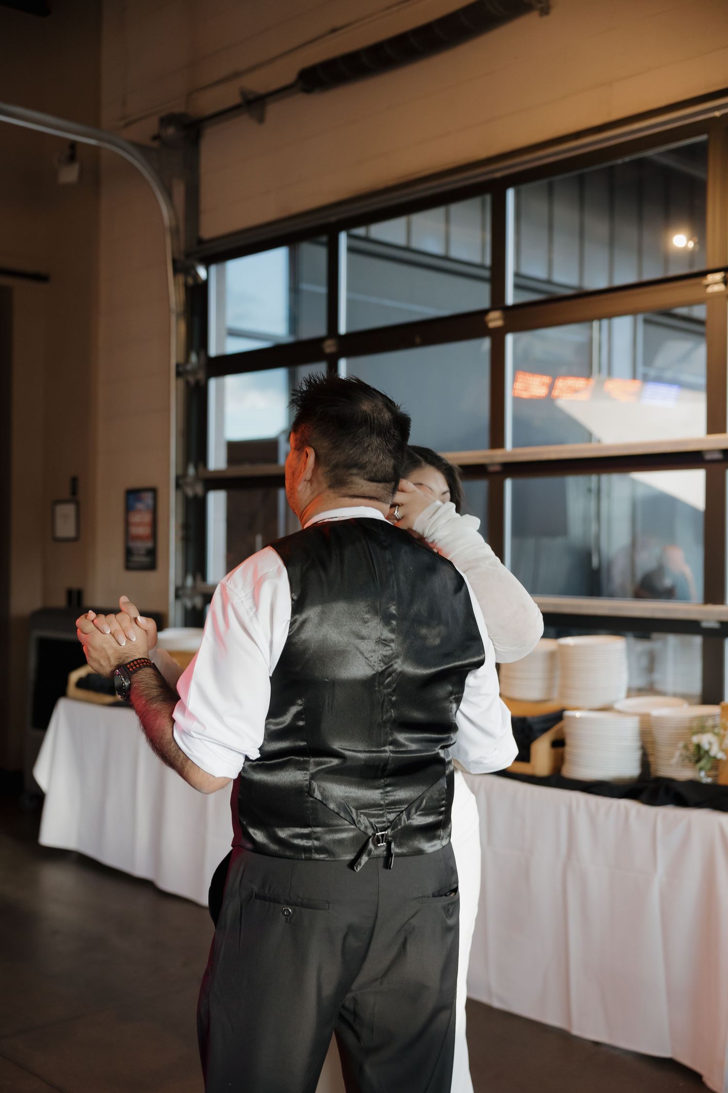 Father daughter dance at wedding reception, man in vest and white shirt holds bride close.