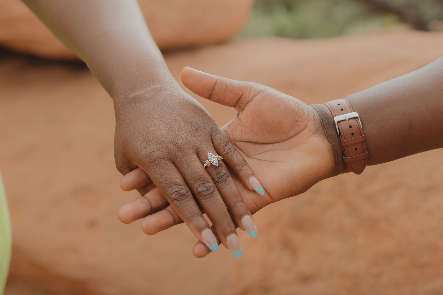 Close-up of hands reaching towards each other in a tender moment outdoors.
