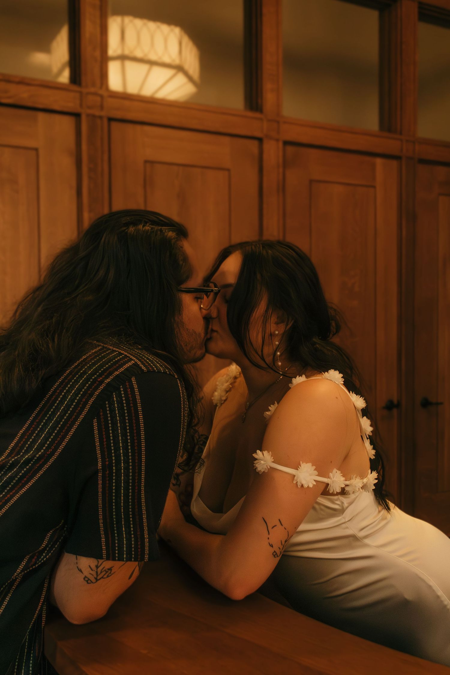 An intimate moment captured in warm lighting against wooden paneled walls.