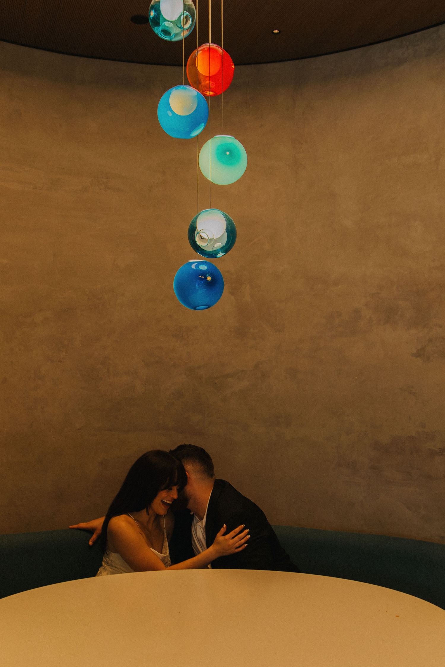 Couple sharing an intimate moment under colorful hanging paper lanterns.