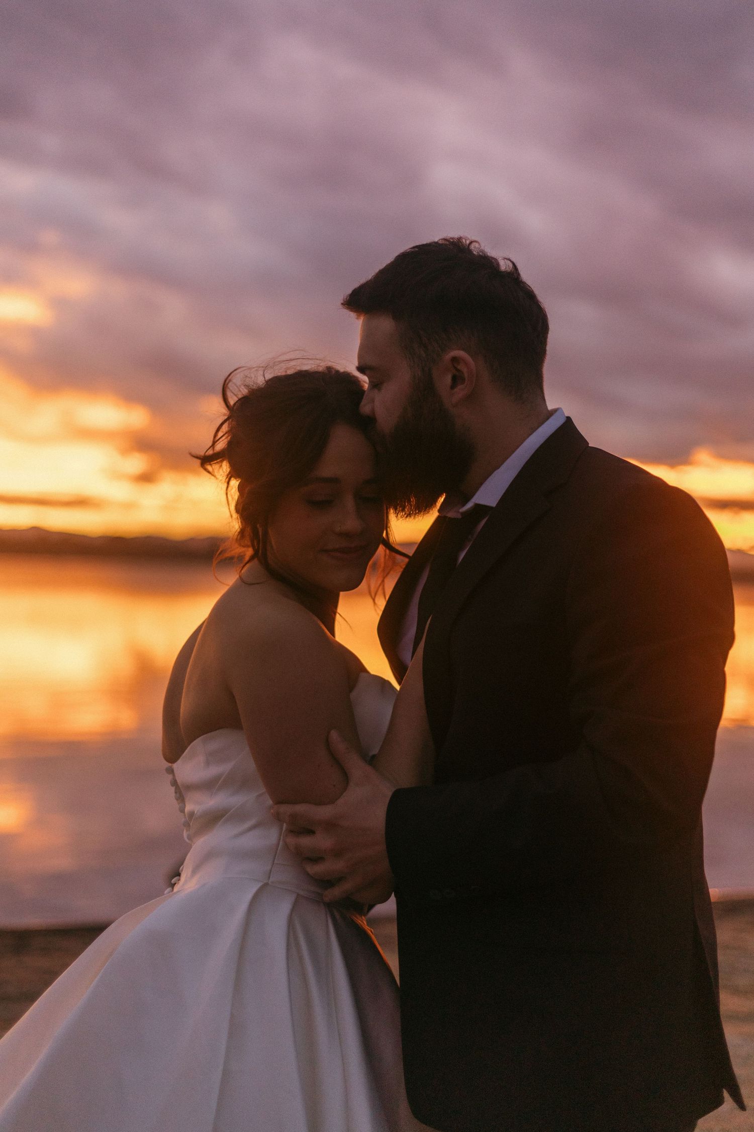 A romantic sunset silhouette of newlyweds embracing on their wedding day.