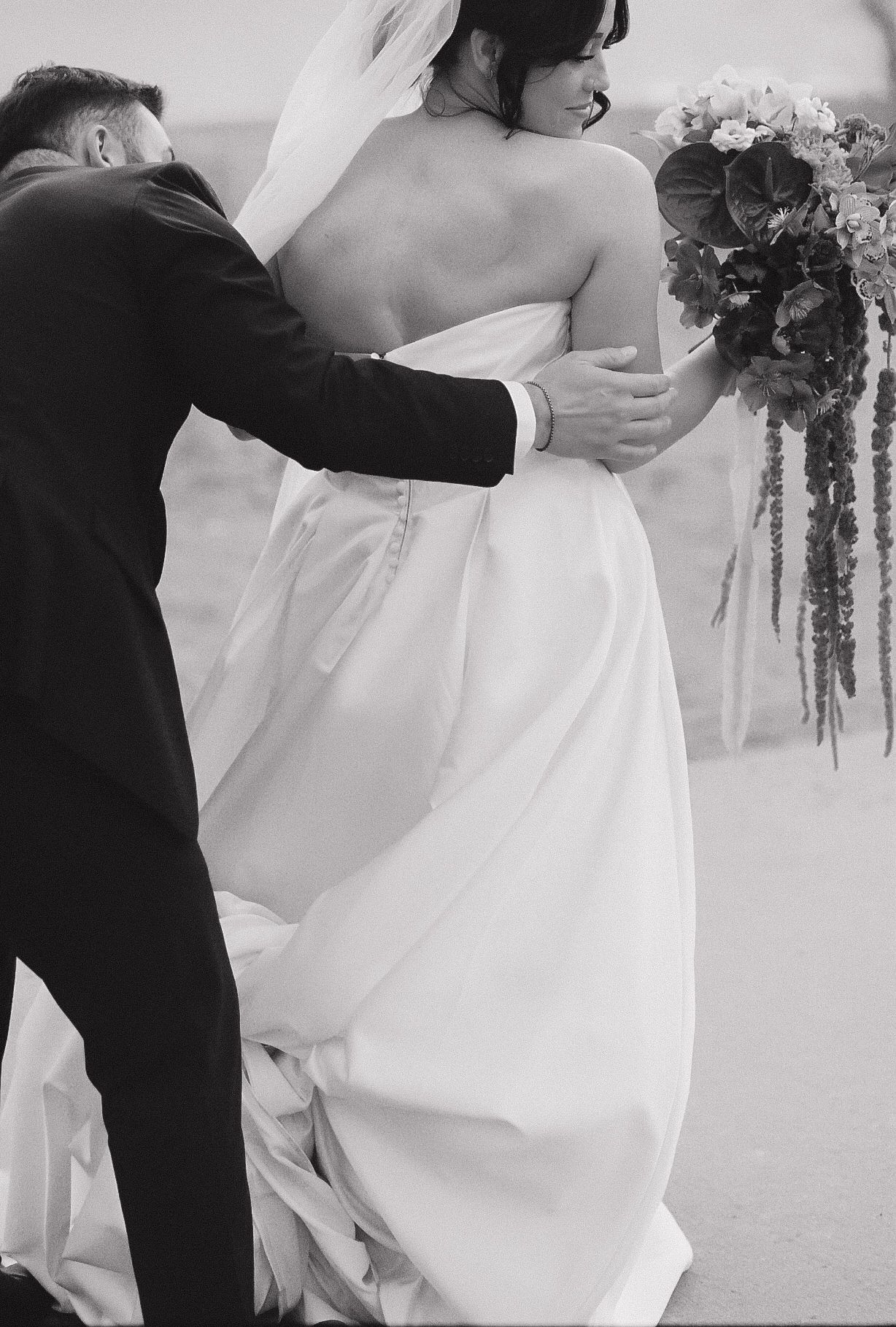 Intimate wedding moment captured in black and white with flowing dress details.