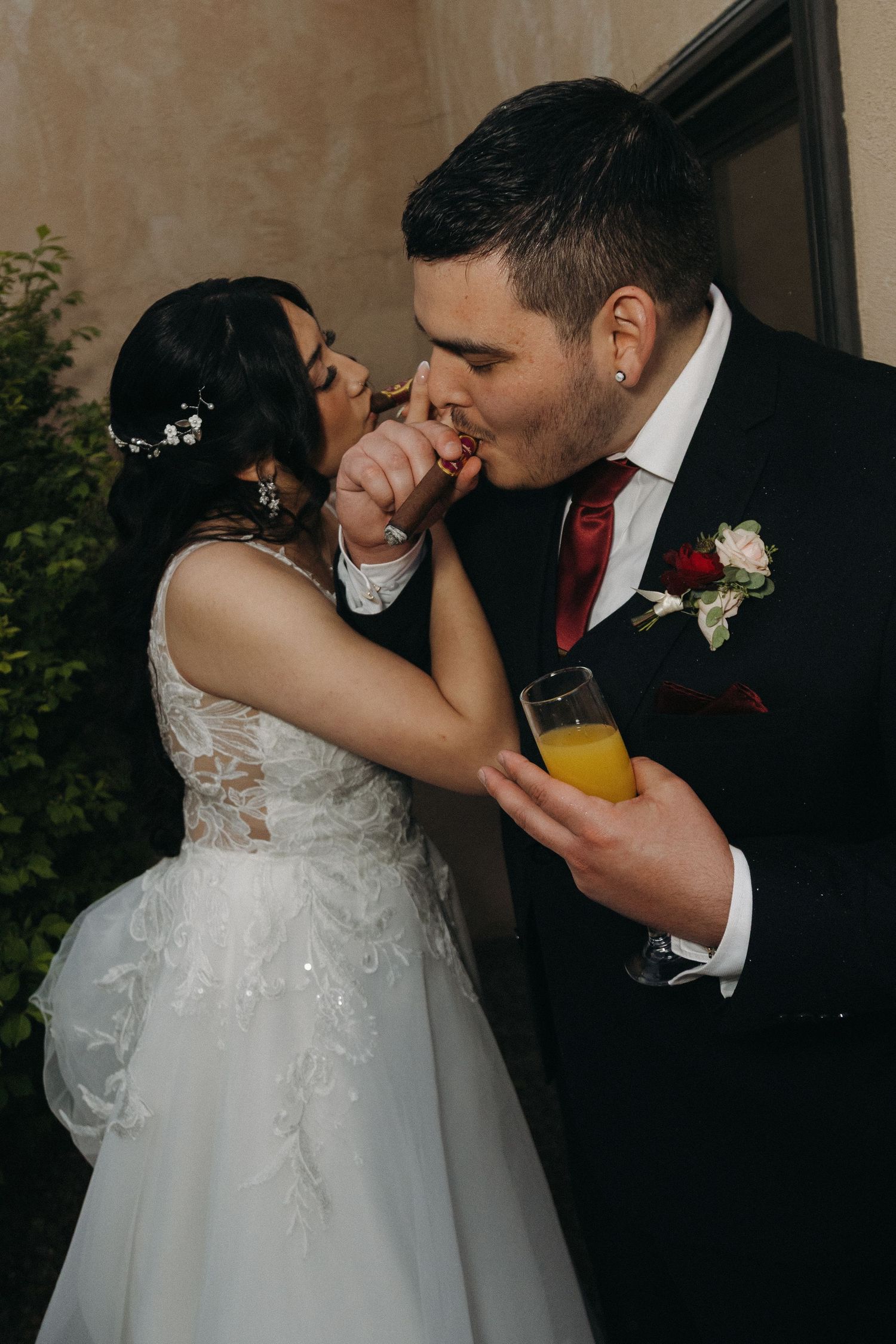 Bride and groom share a tender moment as groom kisses bride's hand while holding a glass of champagne.