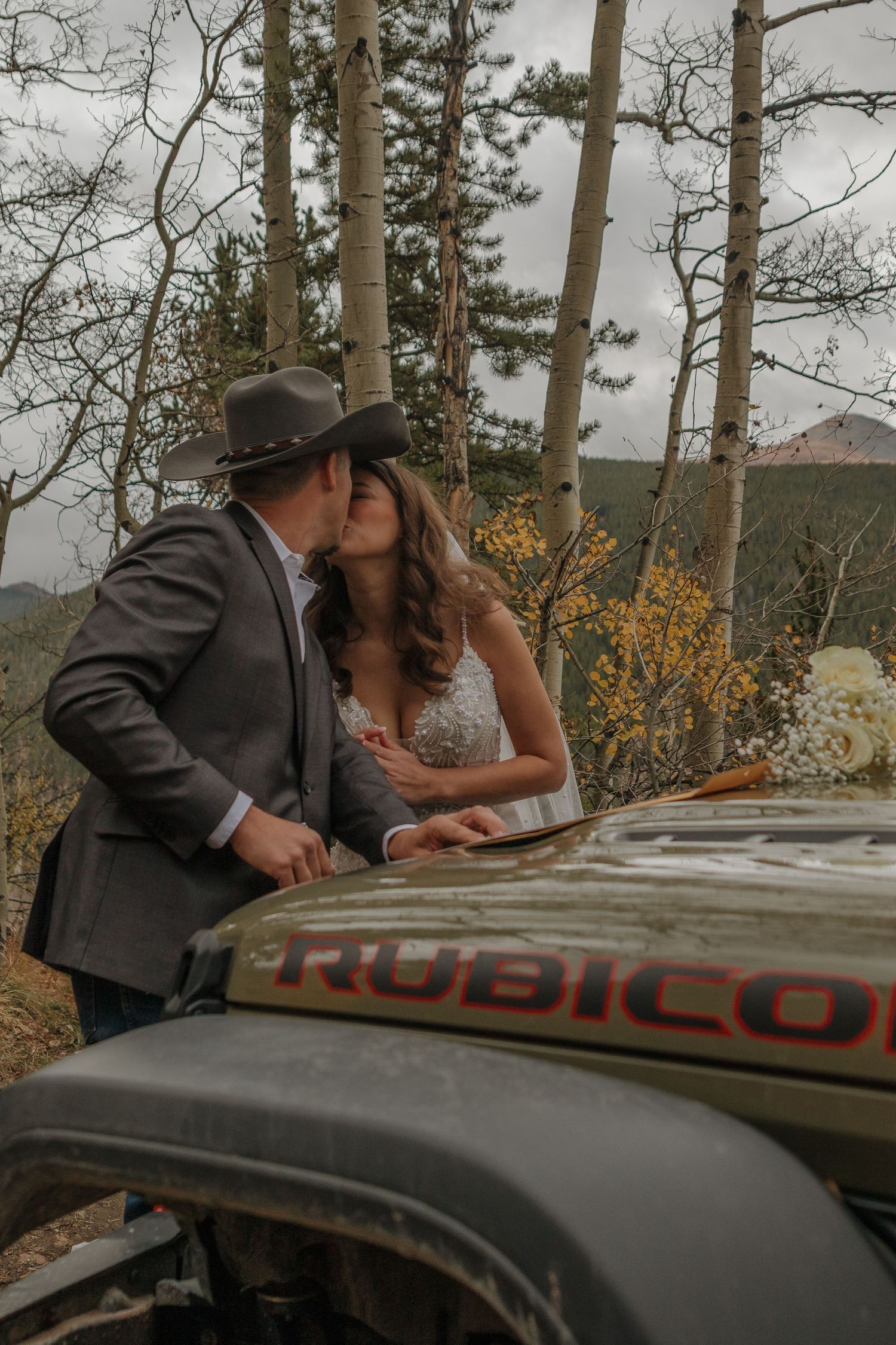 A romantic moment shared against a Jeep Rubicon in an autumn mountain setting.