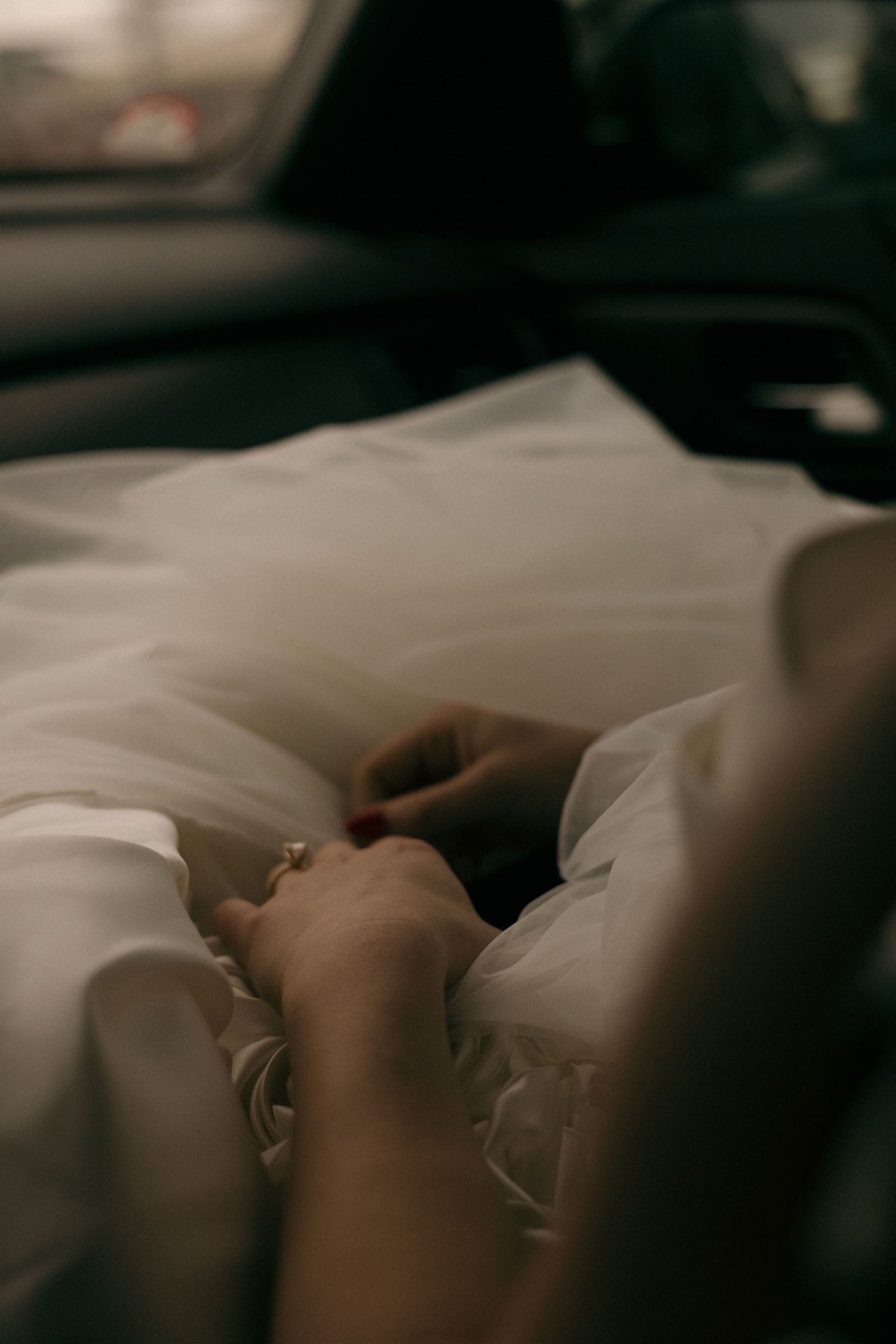 Artistic boudoir photography with soft natural lighting and white bedding.