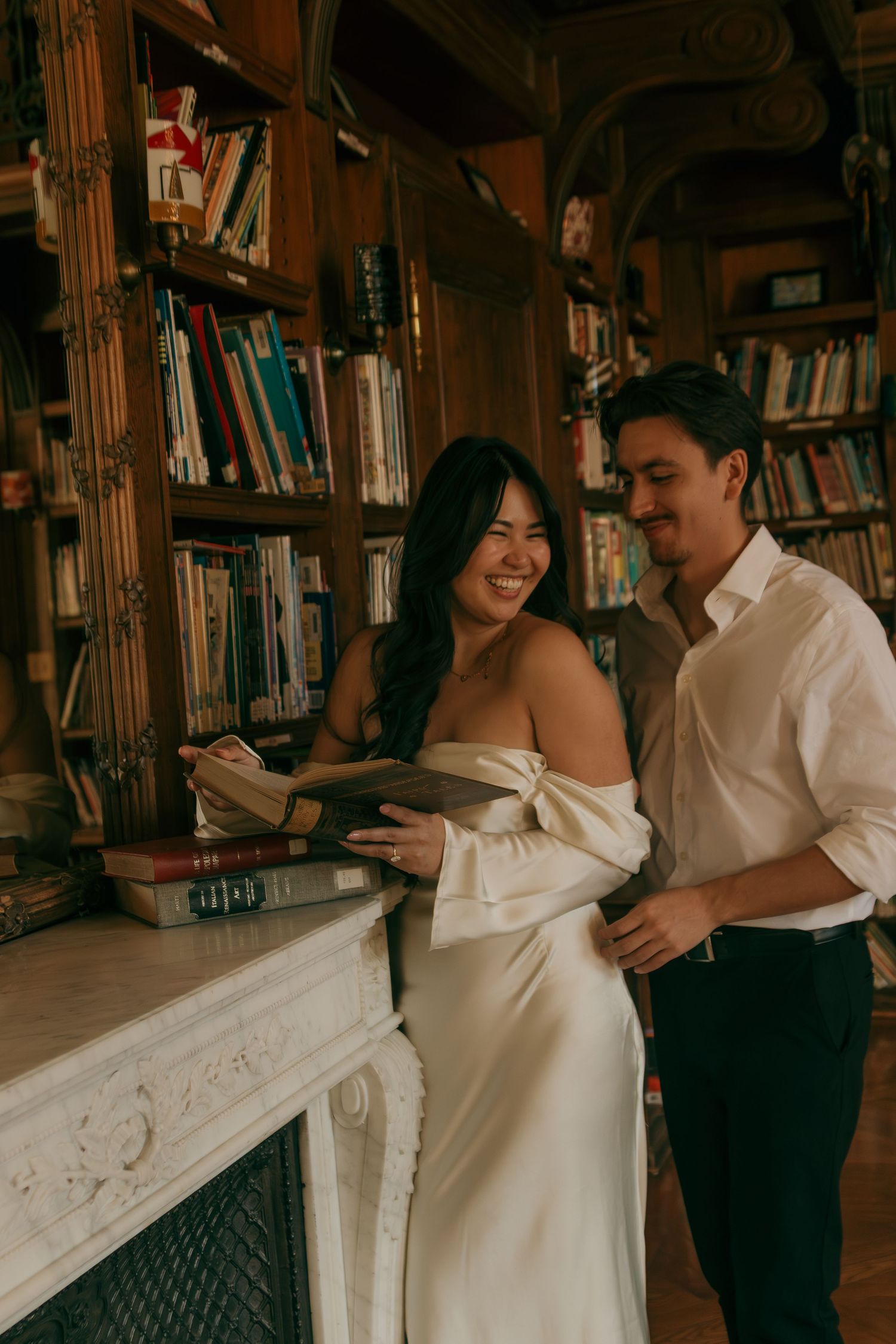 A couple shares an intimate moment while browsing books together in a cozy library setting.