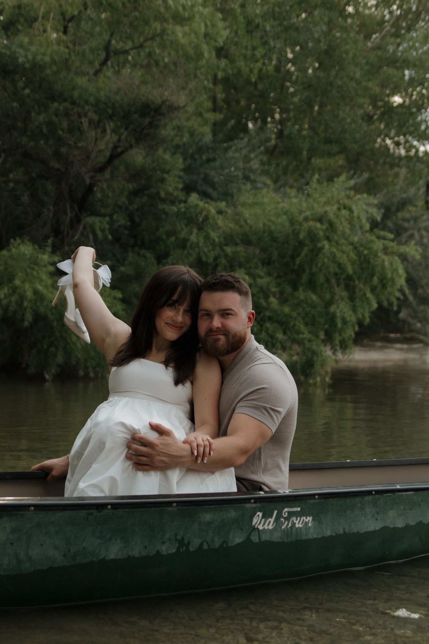 A romantic couple sharing an intimate moment in a green canoe on a scenic lake.