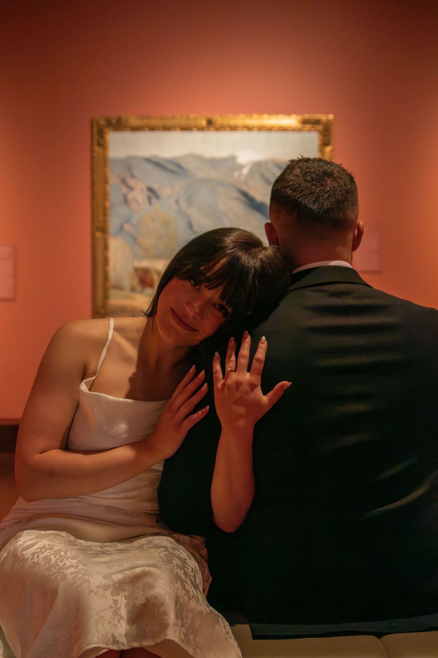 A romantic moment captured in an art gallery with salmon-colored walls.