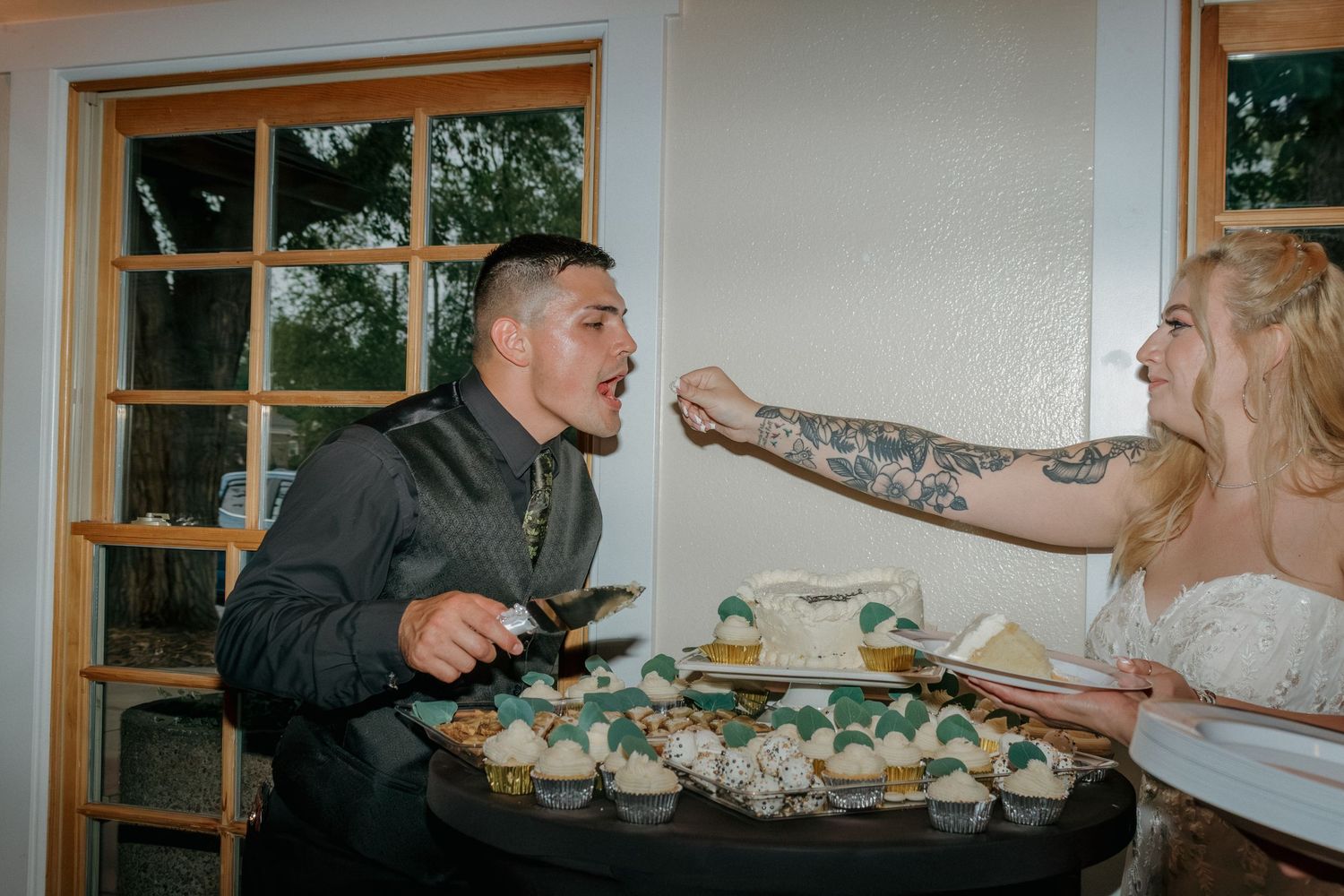 Playful cake feeding moment between couple at wedding reception.