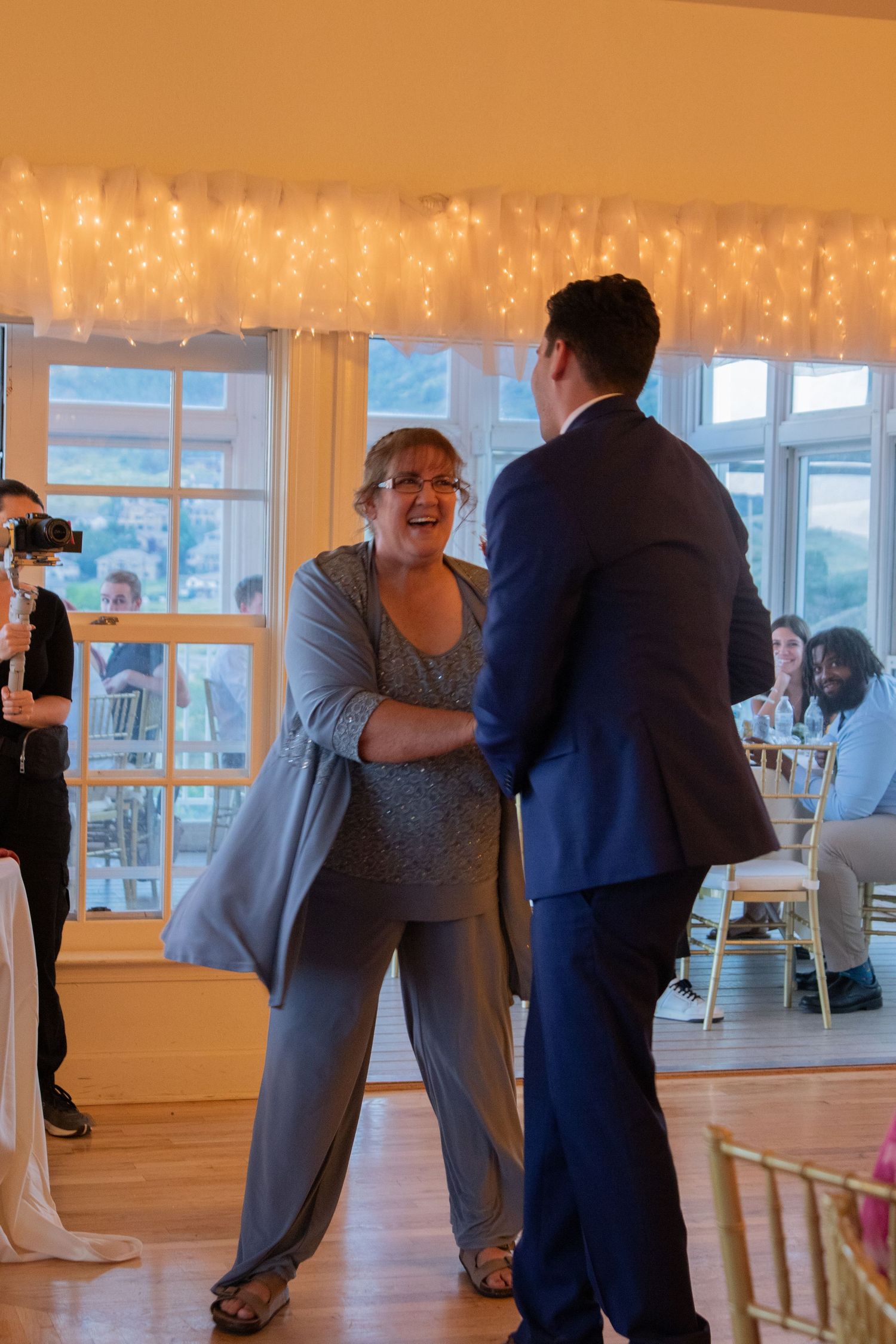Wedding reception dance sequence showing couples dancing in an indoor venue with twinkle lights.