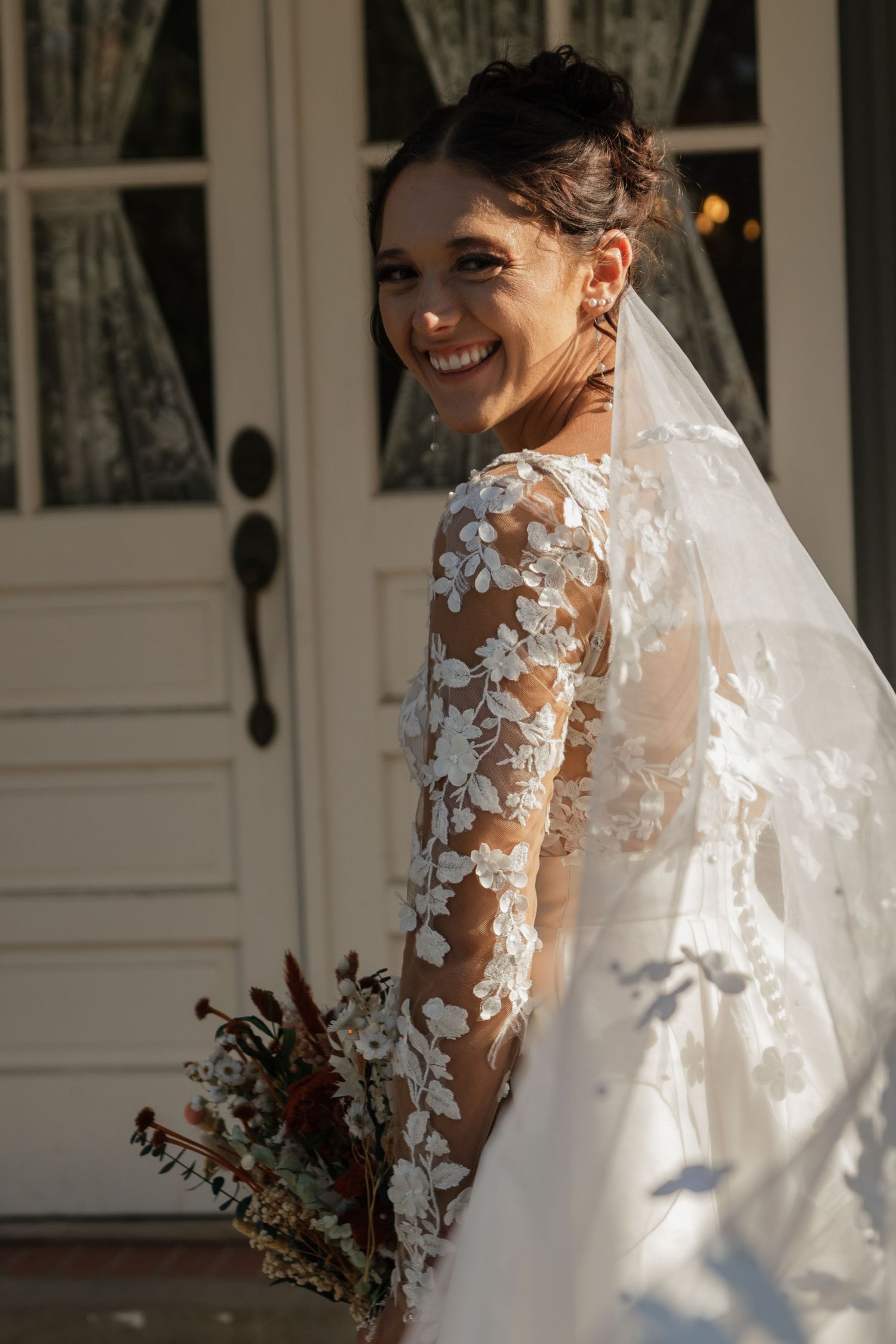 A wedding dress featuring delicate lace sleeves and floral appliques in natural sunlight.