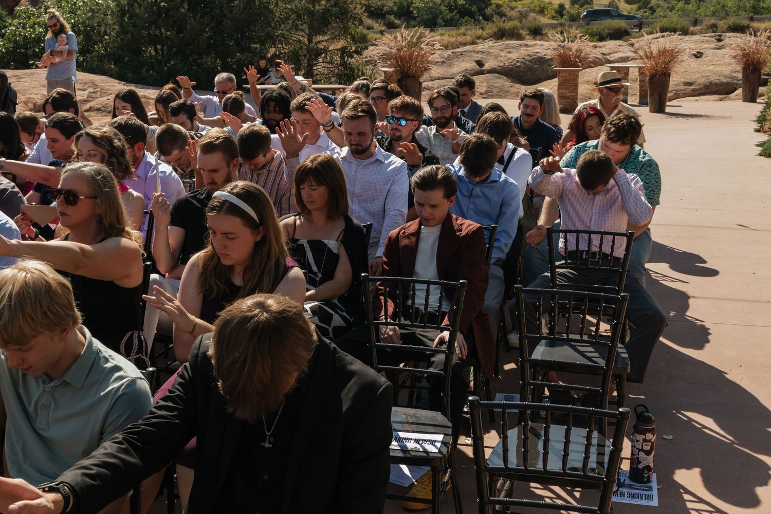 Wedding guests seated in rows of chairs at an outdoor ceremony venue.