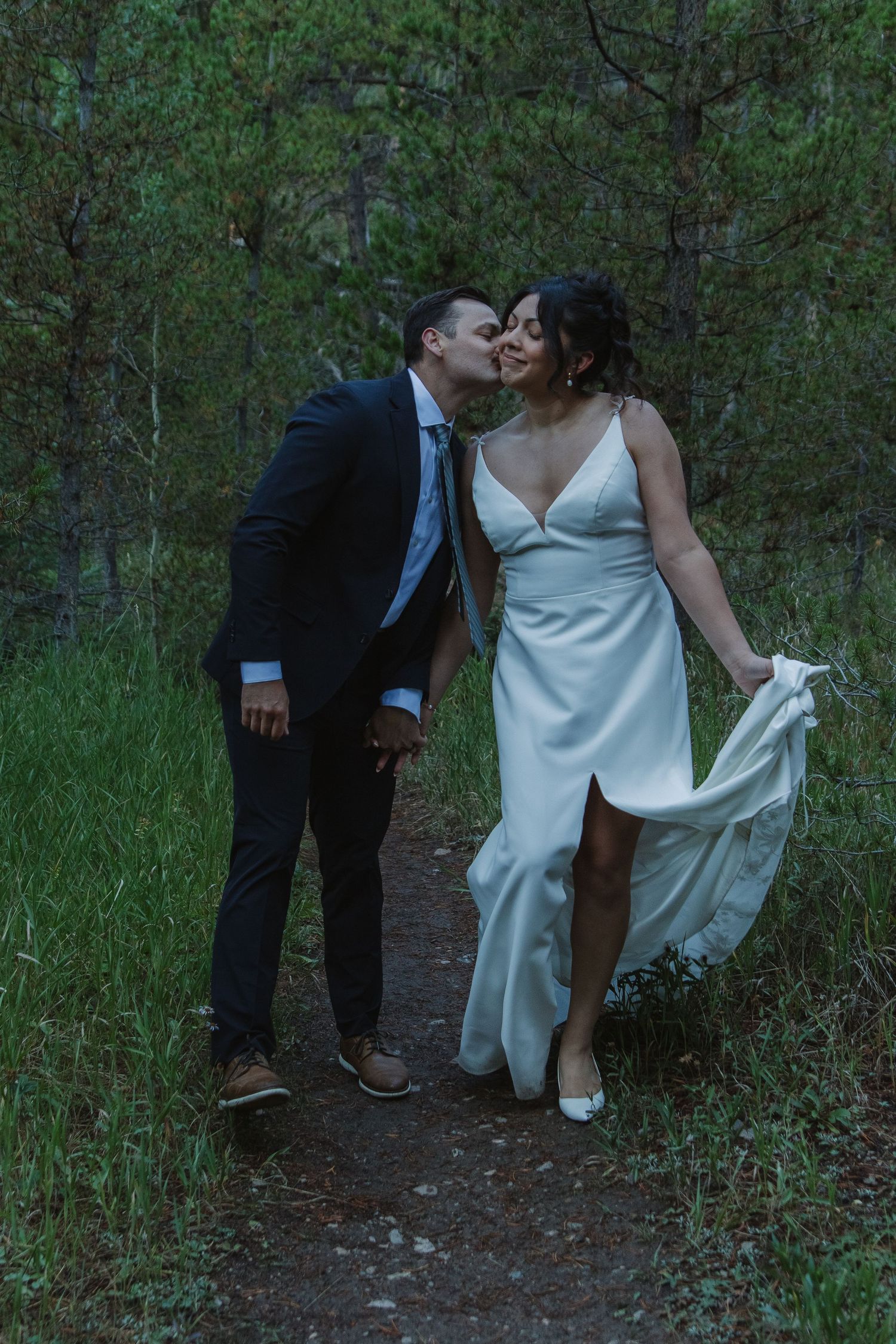 Wedding couple explores a forest path together with playful and intimate moments.