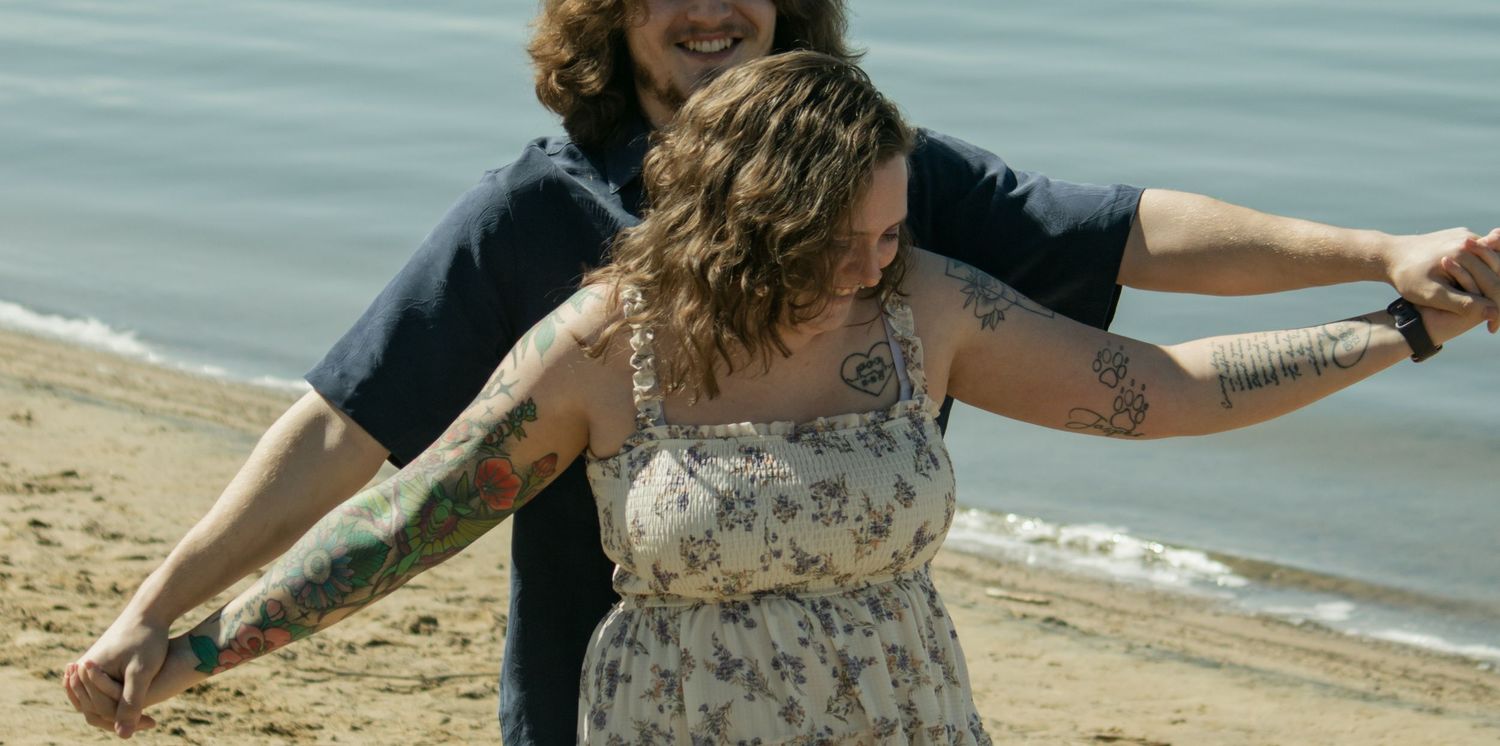 A couple dancing together on a beach with waves in the background.