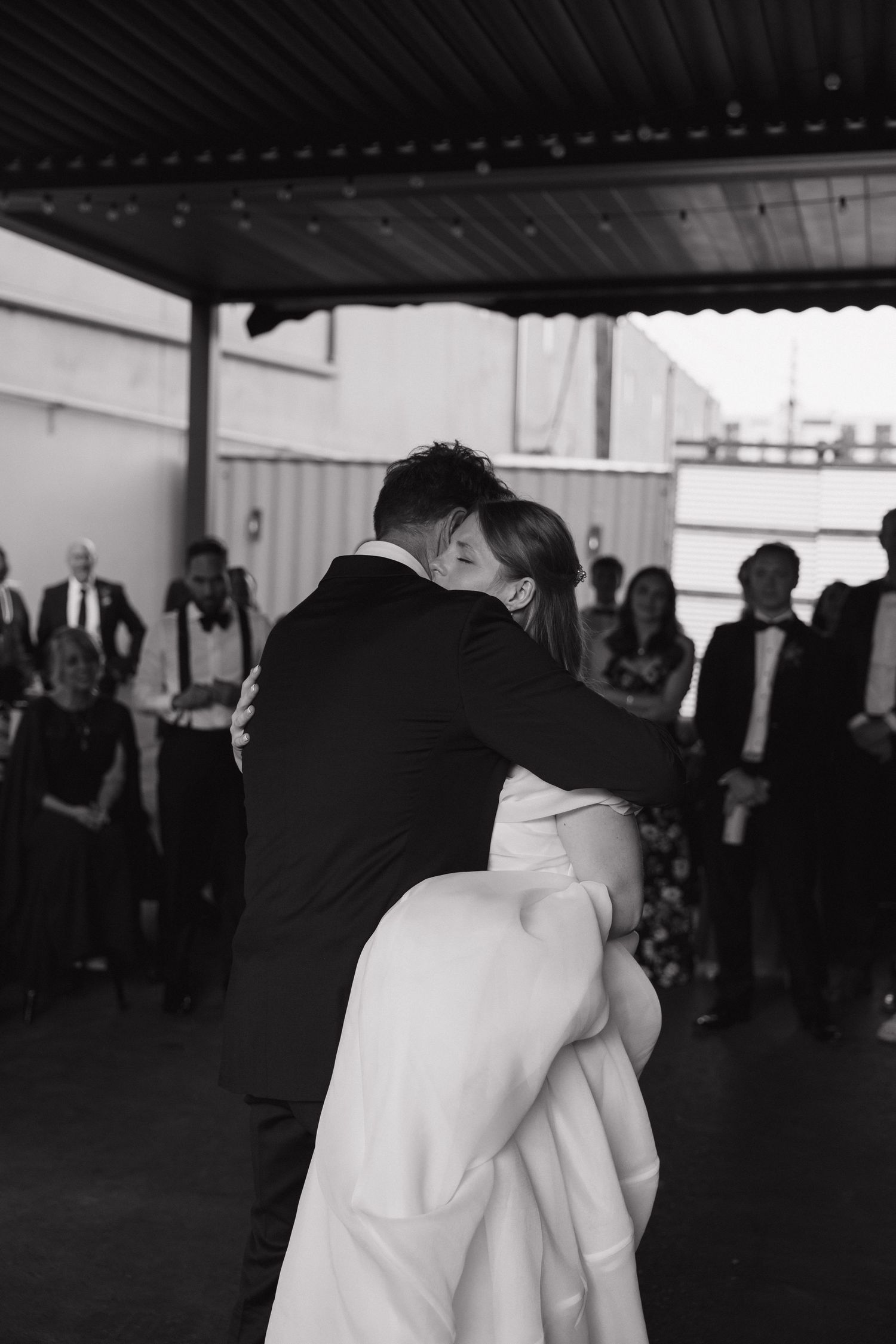 Groom lifting bride during their first dance at wedding reception in black and white photography.