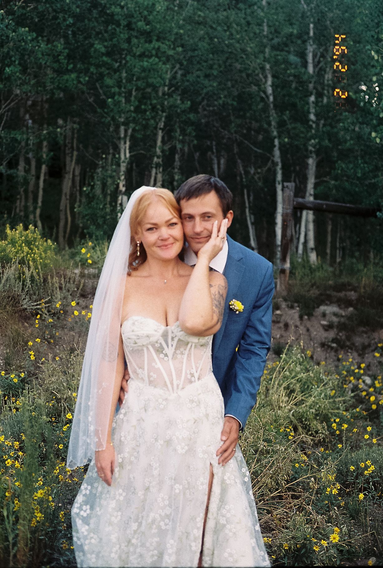 Film photo of bride in lace gown and groom in blue suit posing in aspen grove.