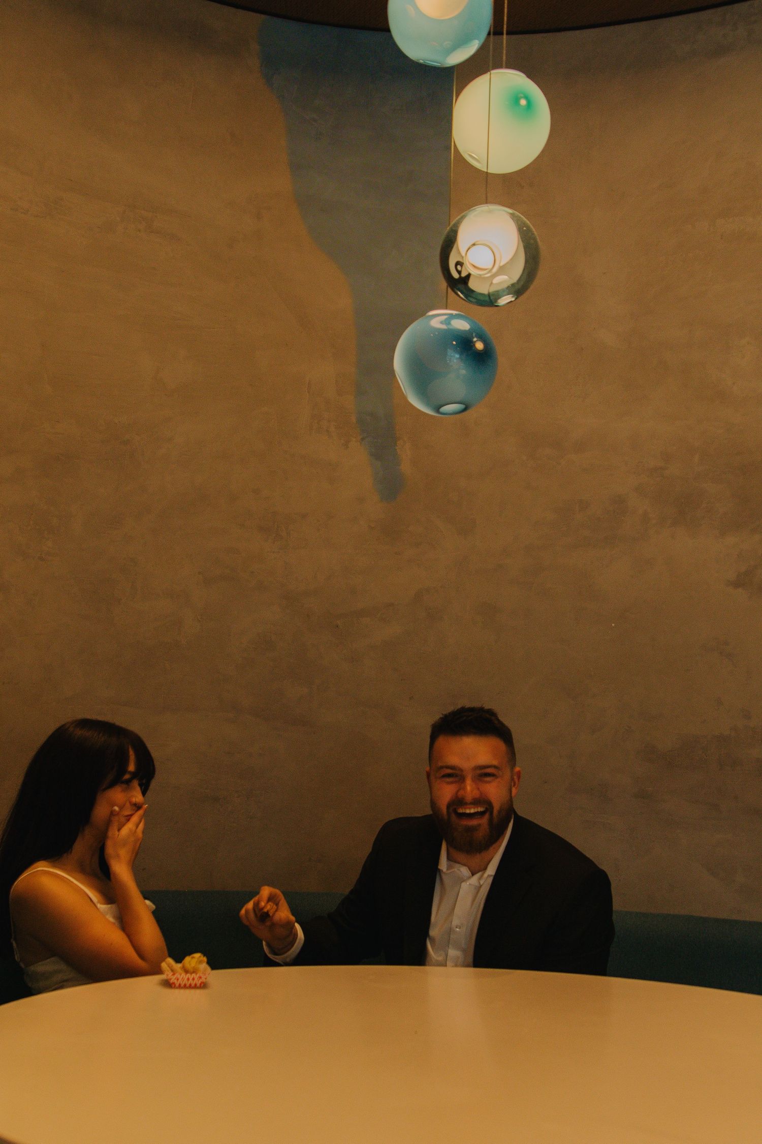 Couple sharing laughter under modern pendant lighting.