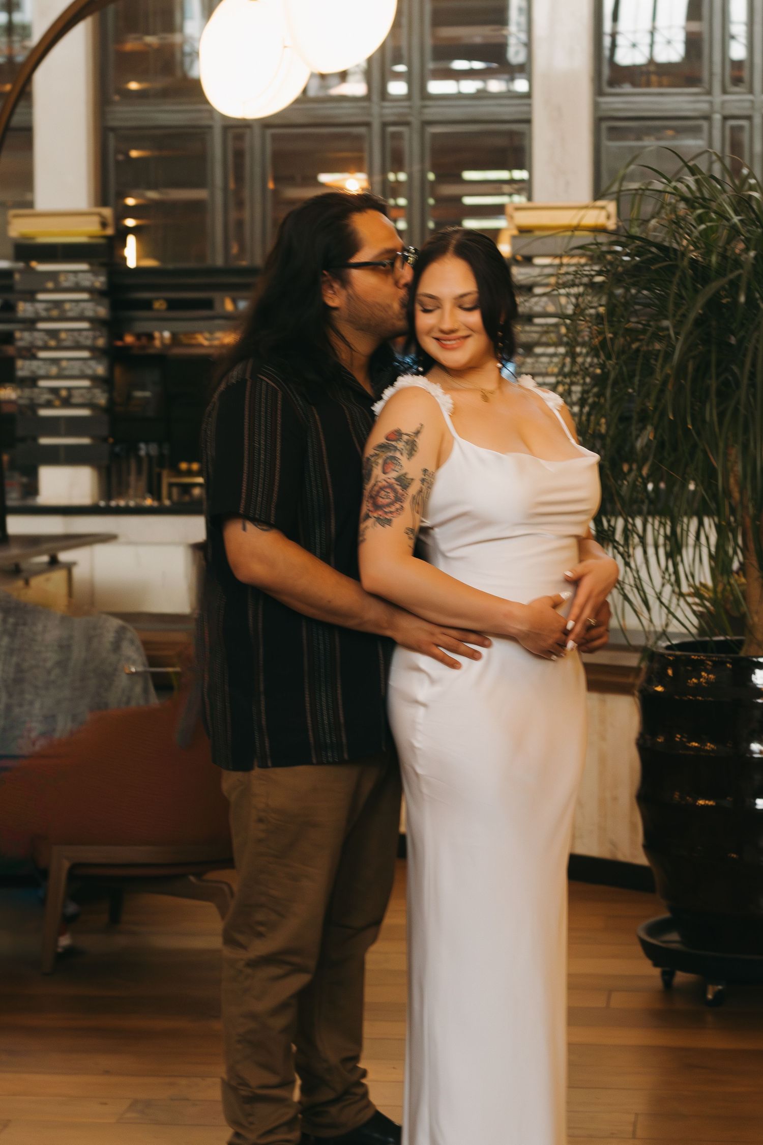 A couple shares a romantic moment in a warmly lit restaurant interior.