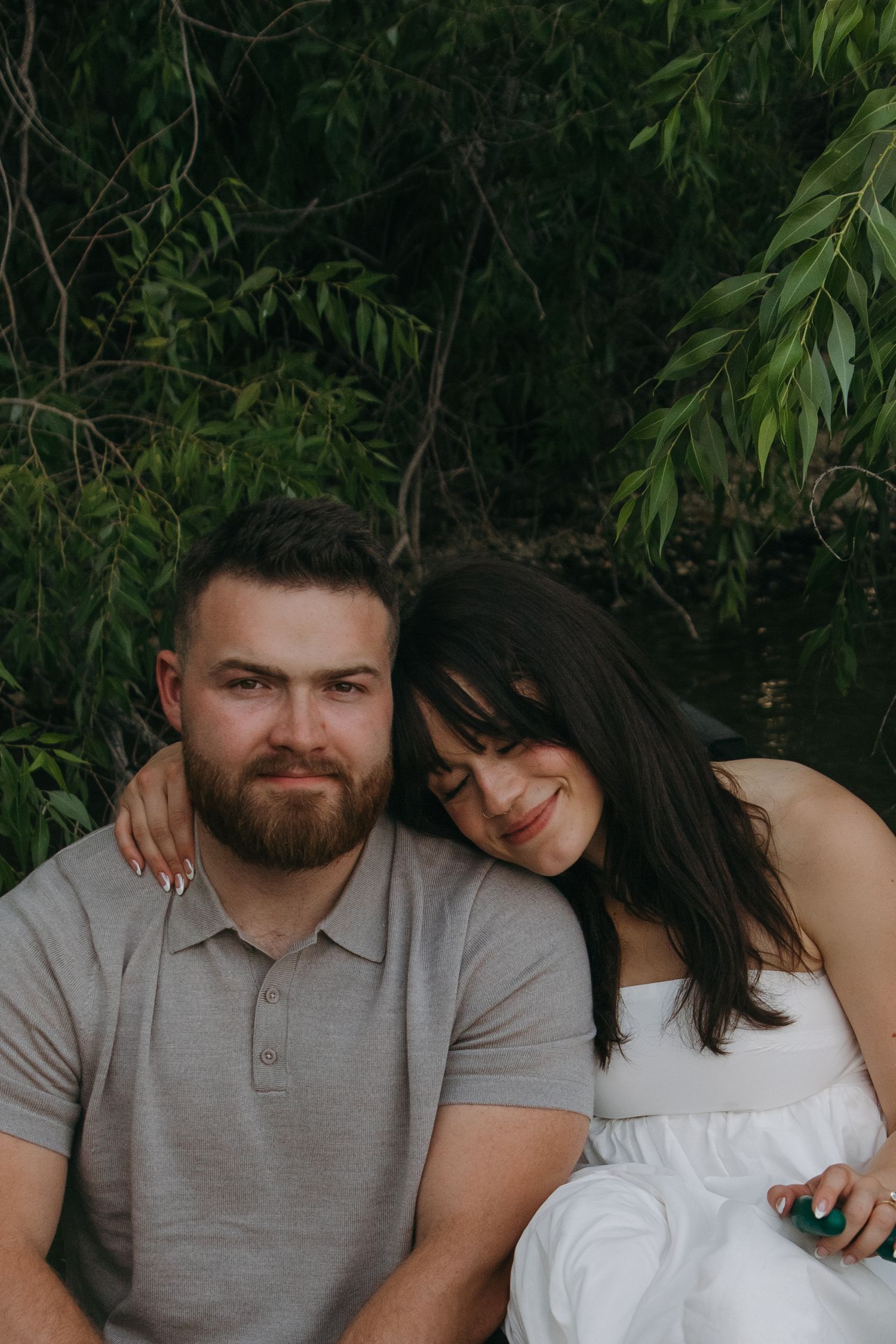 A tender couple moment against a lush green backdrop of foliage and trees.