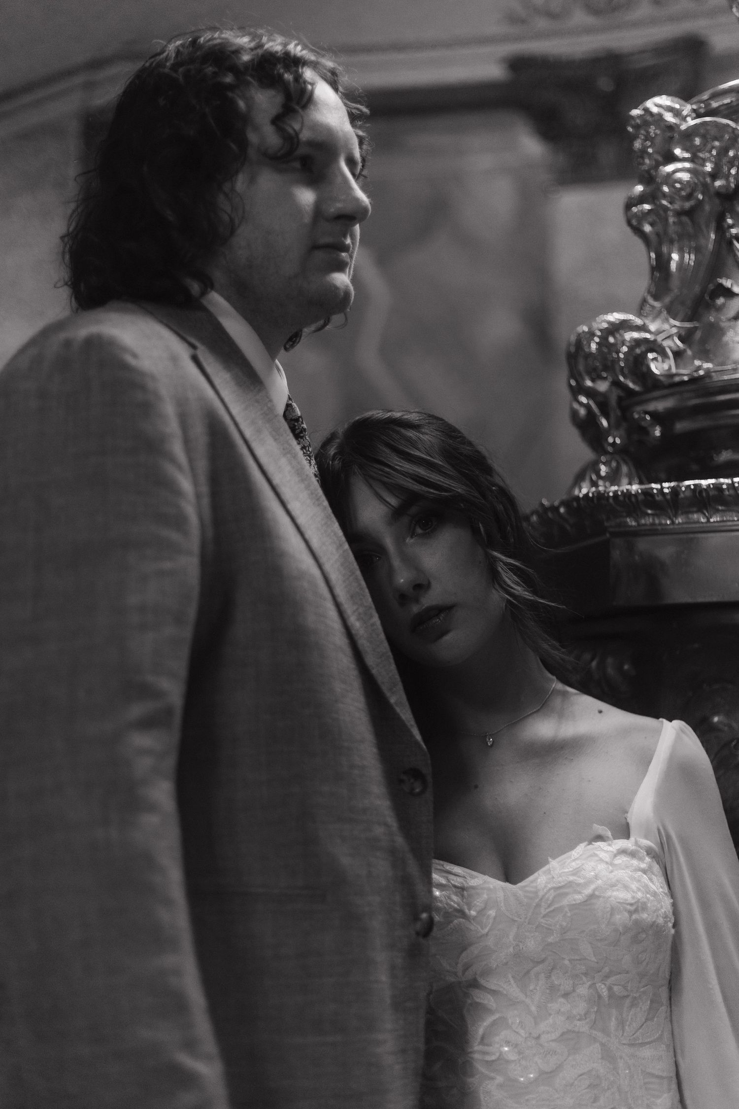 An intimate black and white portrait of a couple posing near an ornate fixture.