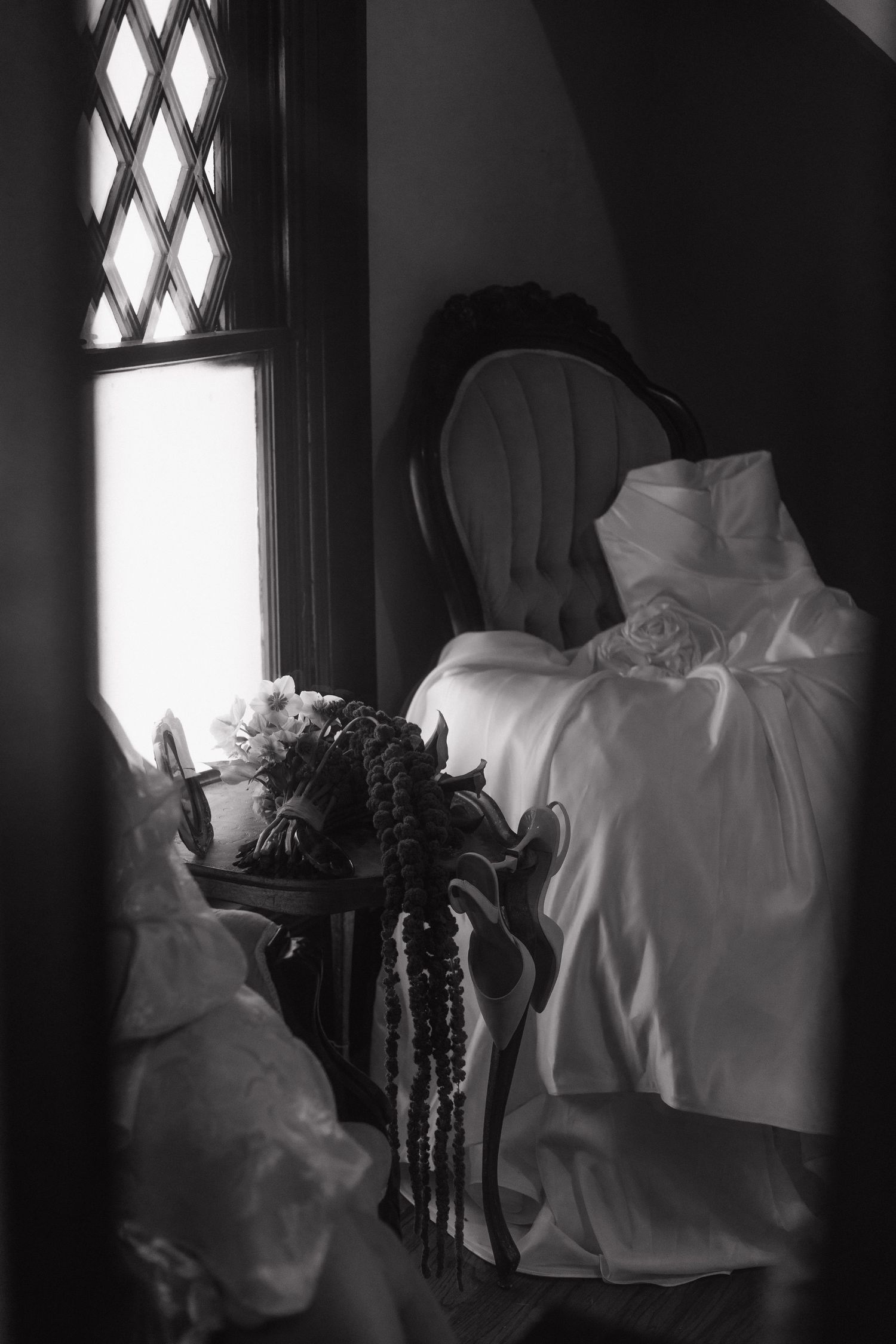 A series of dark and moody black and white photos showing white fabric draped over furniture near a window.