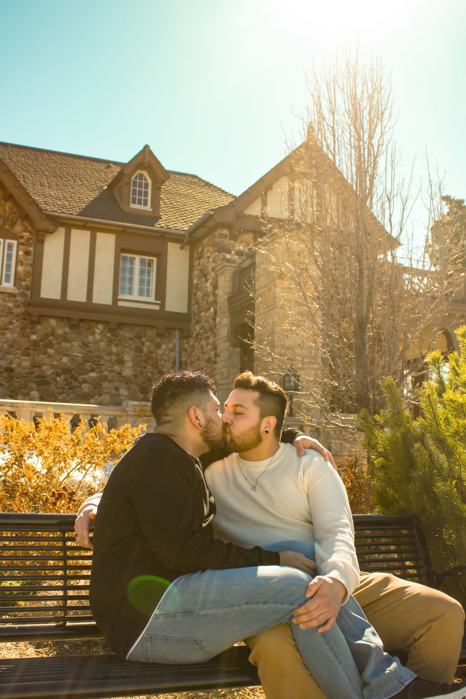 Couple relaxing on bench with stone buildings and autumn foliage creating romantic backdrop.