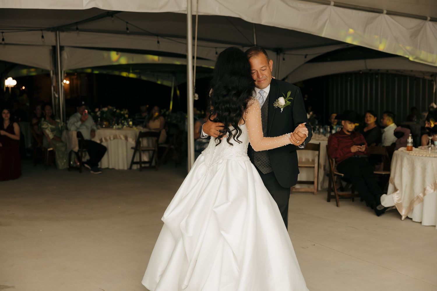 Bride and father share emotional first dance under tent at wedding reception.