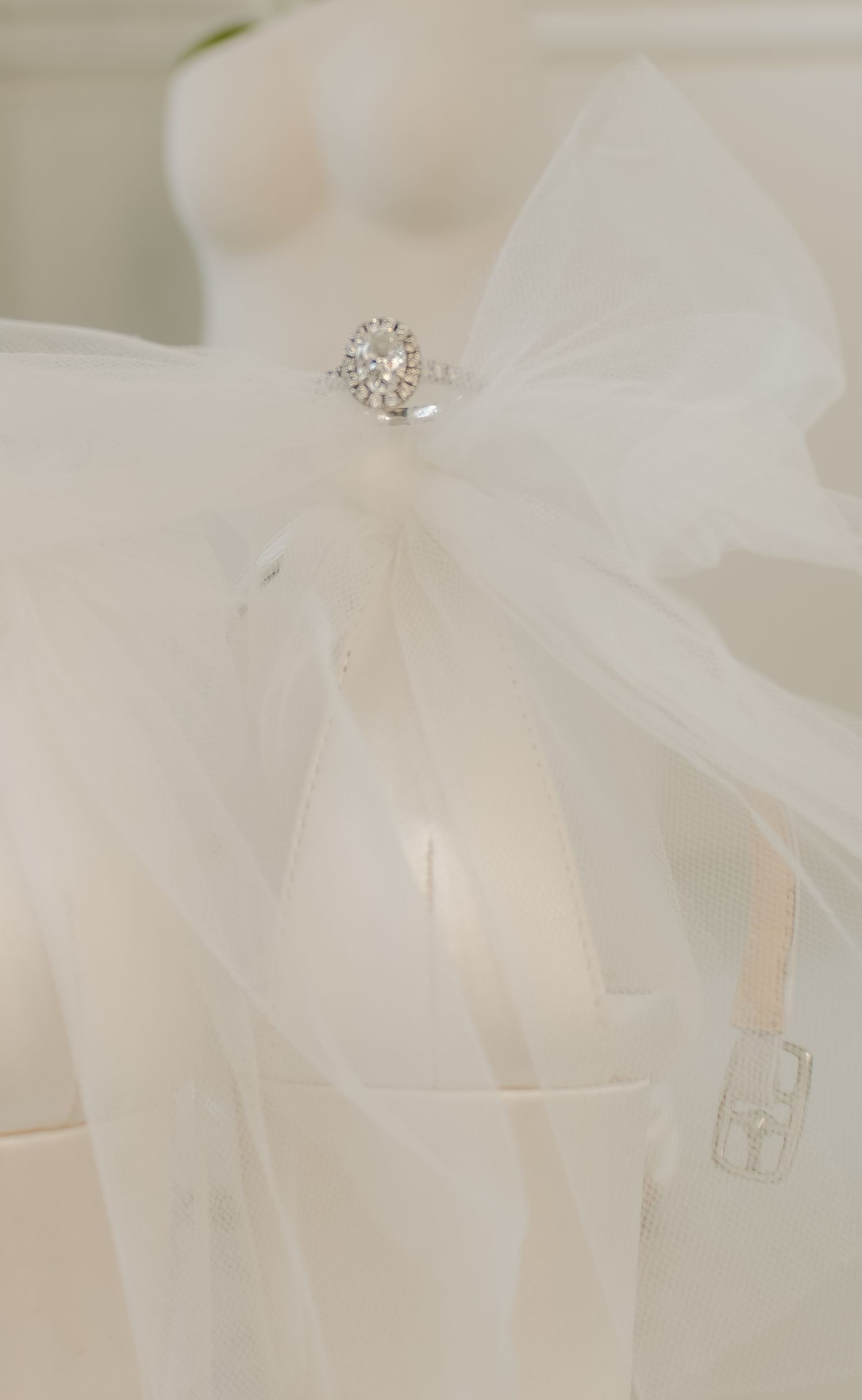Sparkling diamond engagement ring nestled in delicate white tulle fabric.