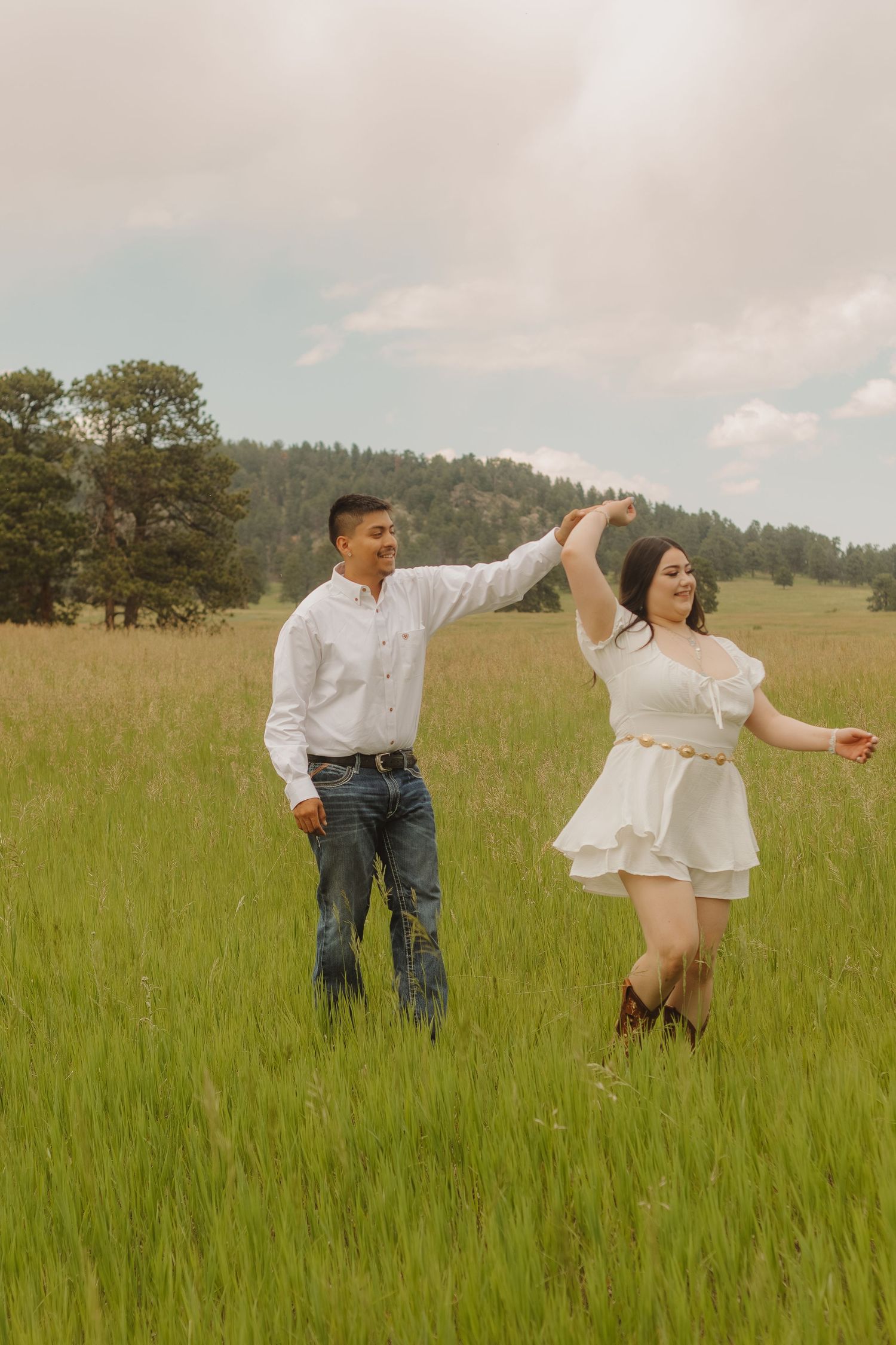 Playful couple dancing and running through tall grass in golden afternoon light.