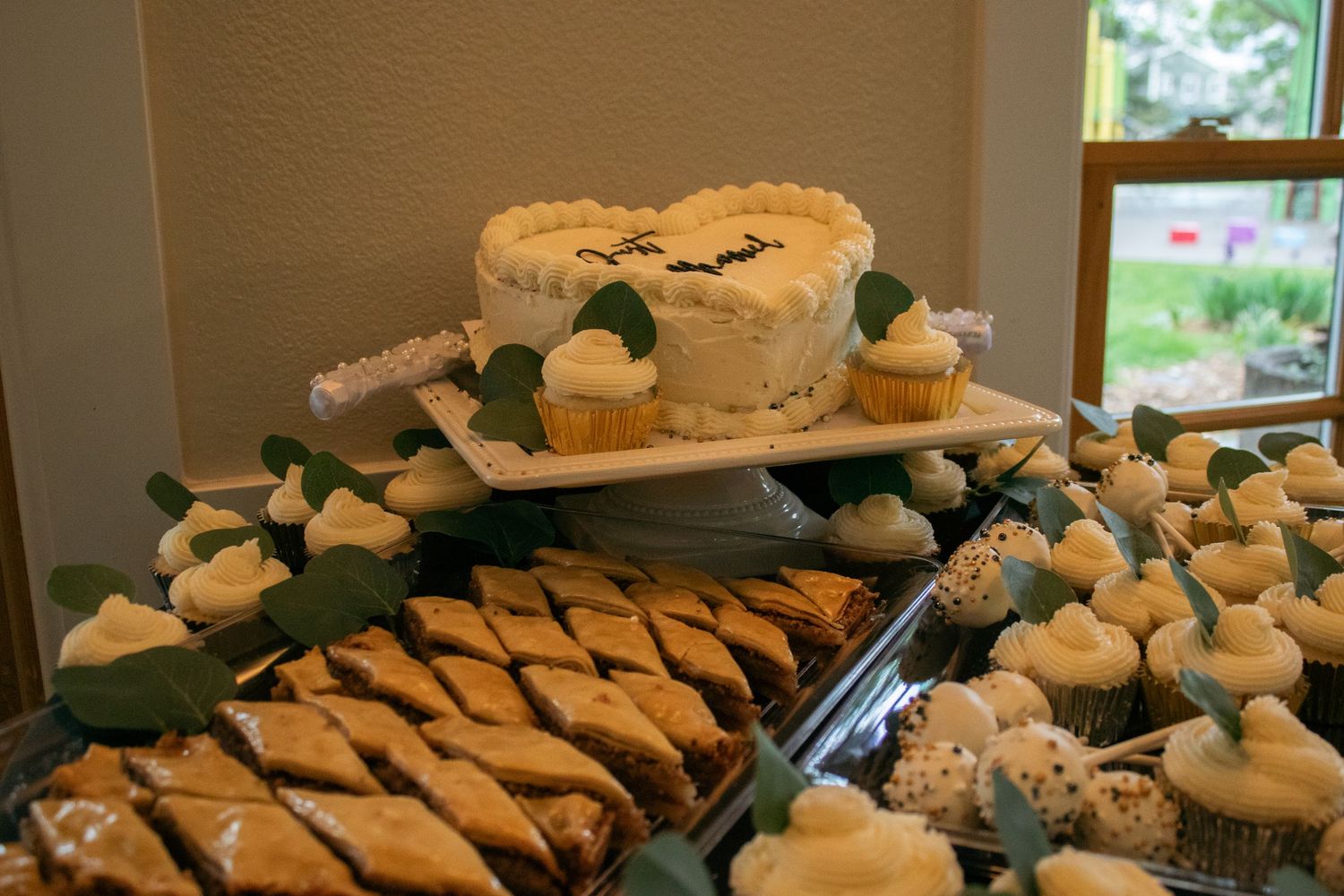 Wedding dessert spread featuring decorated cupcakes and pastries arranged on multiple tiers.