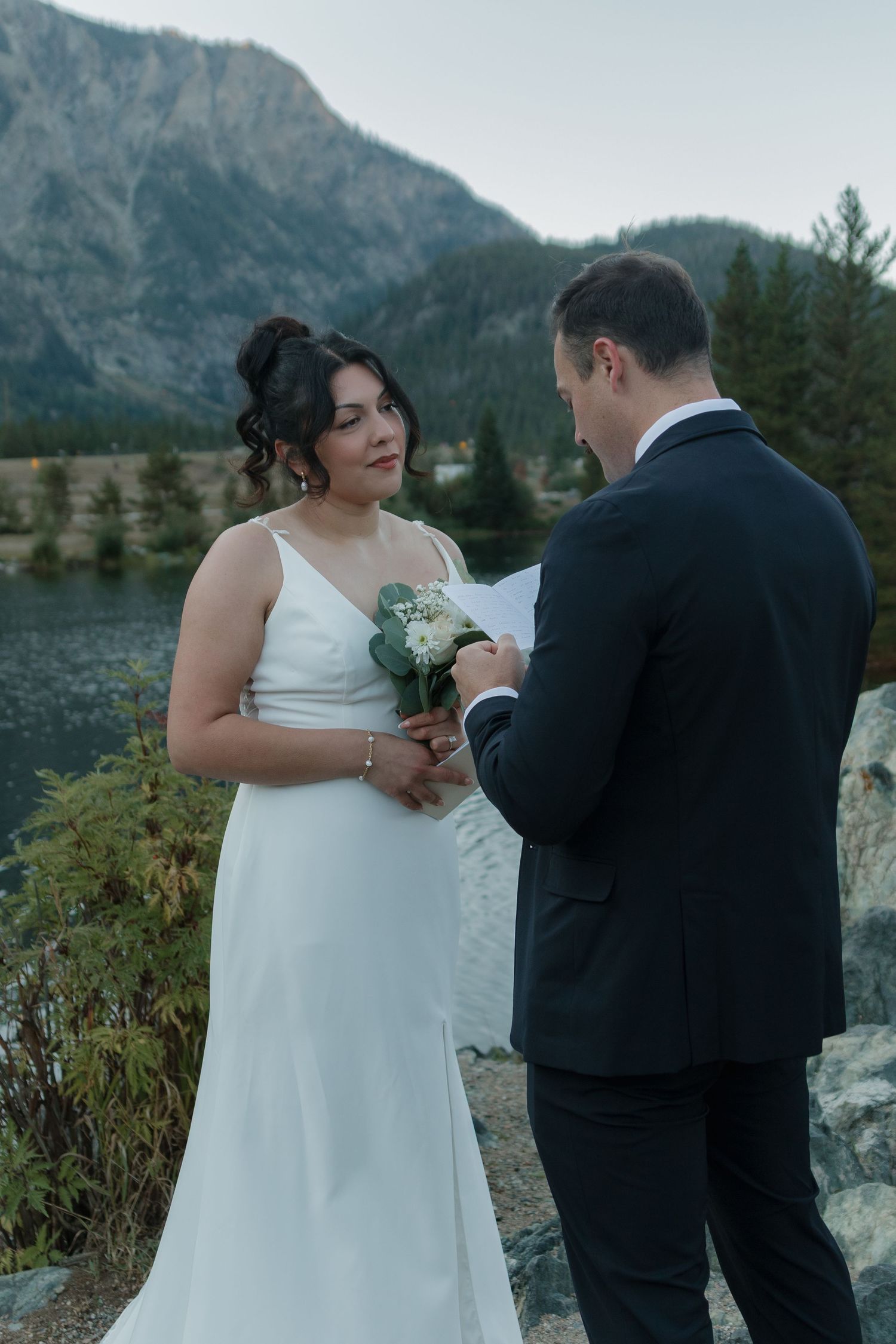 Wedding ceremony taking place on scenic mountain overlook with forest backdrop.