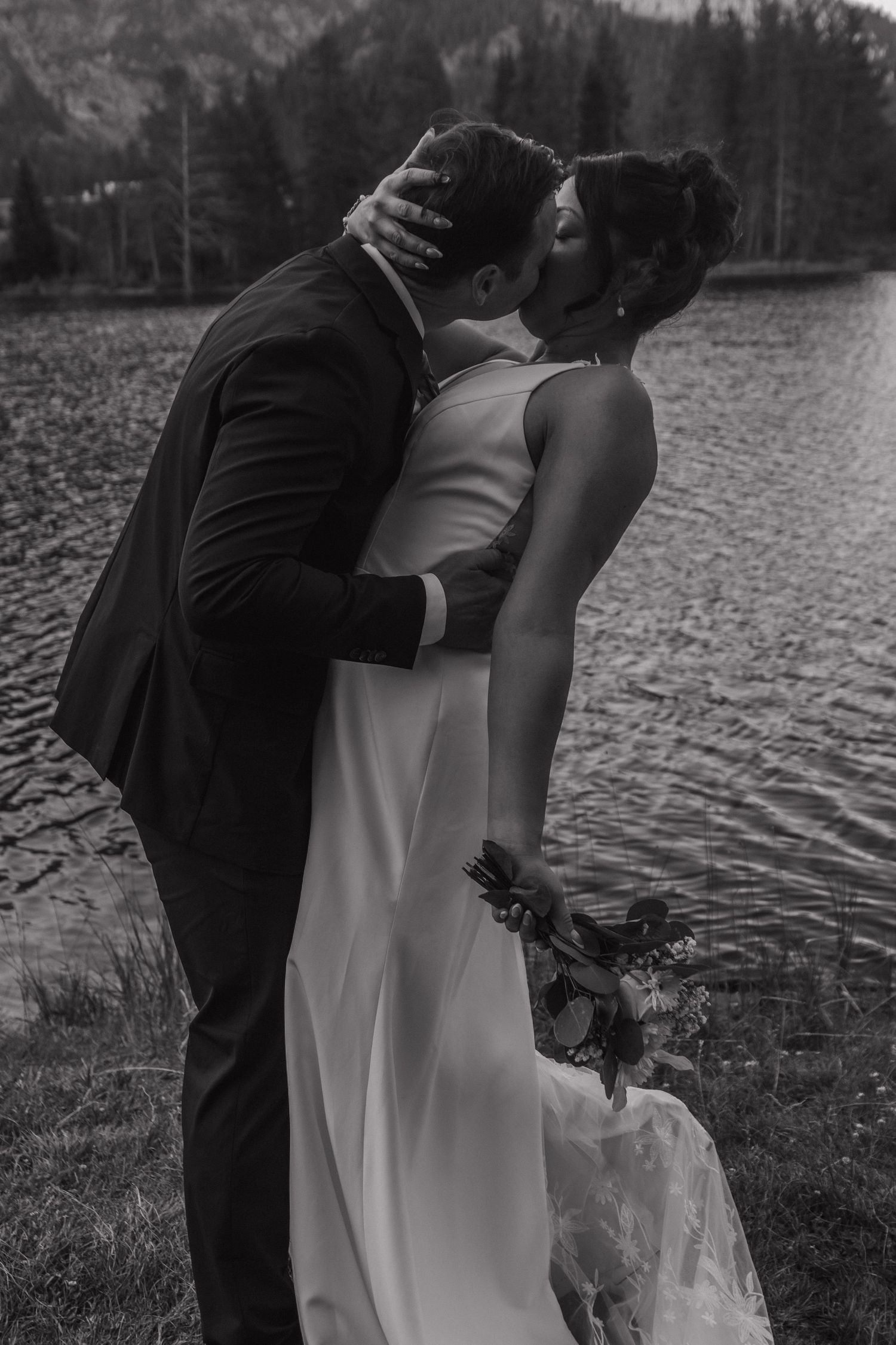 Romantic lakeside wedding photography session with mountain landscape backdrop.