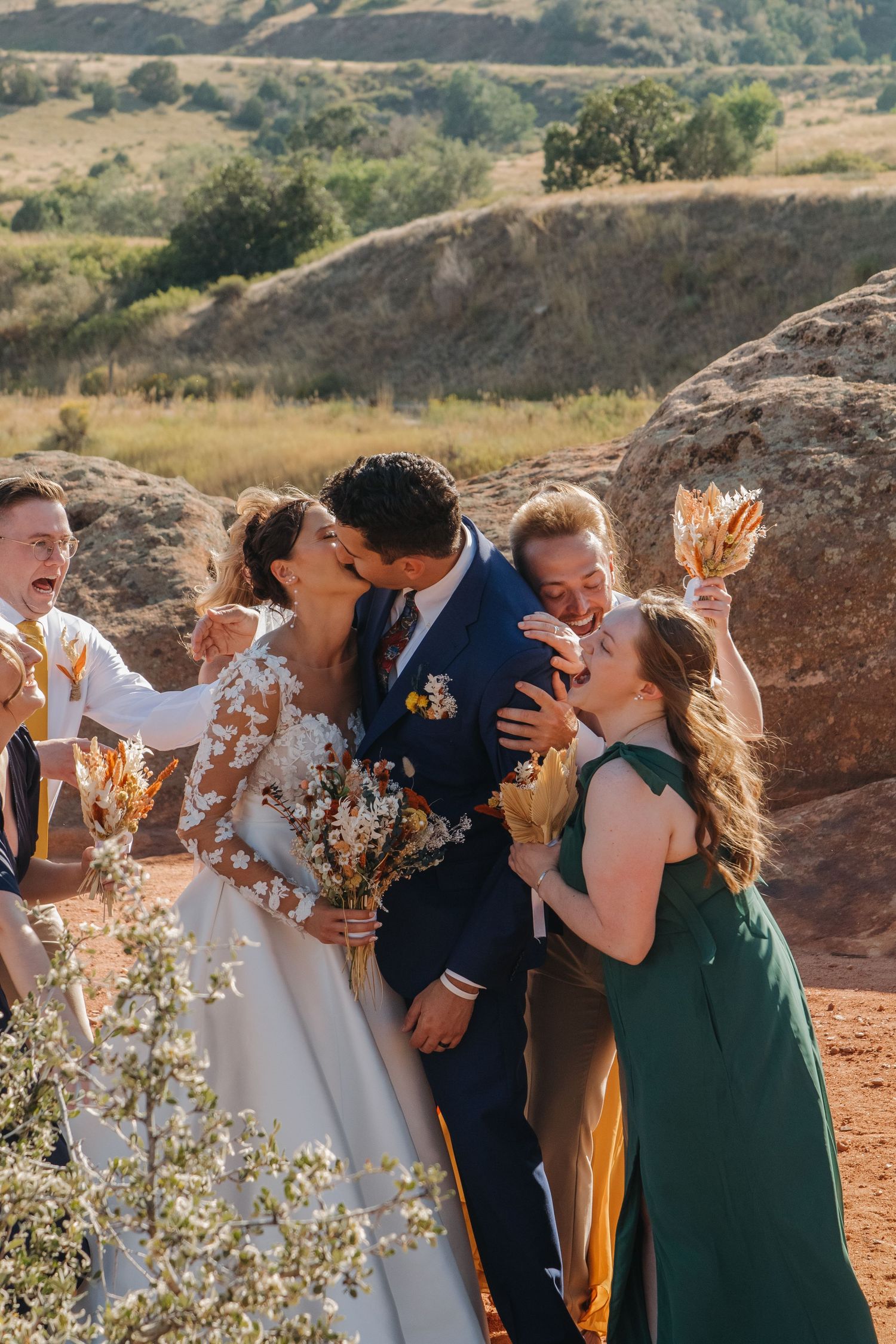 Wedding party members celebrating joyfully against a mountainous backdrop.