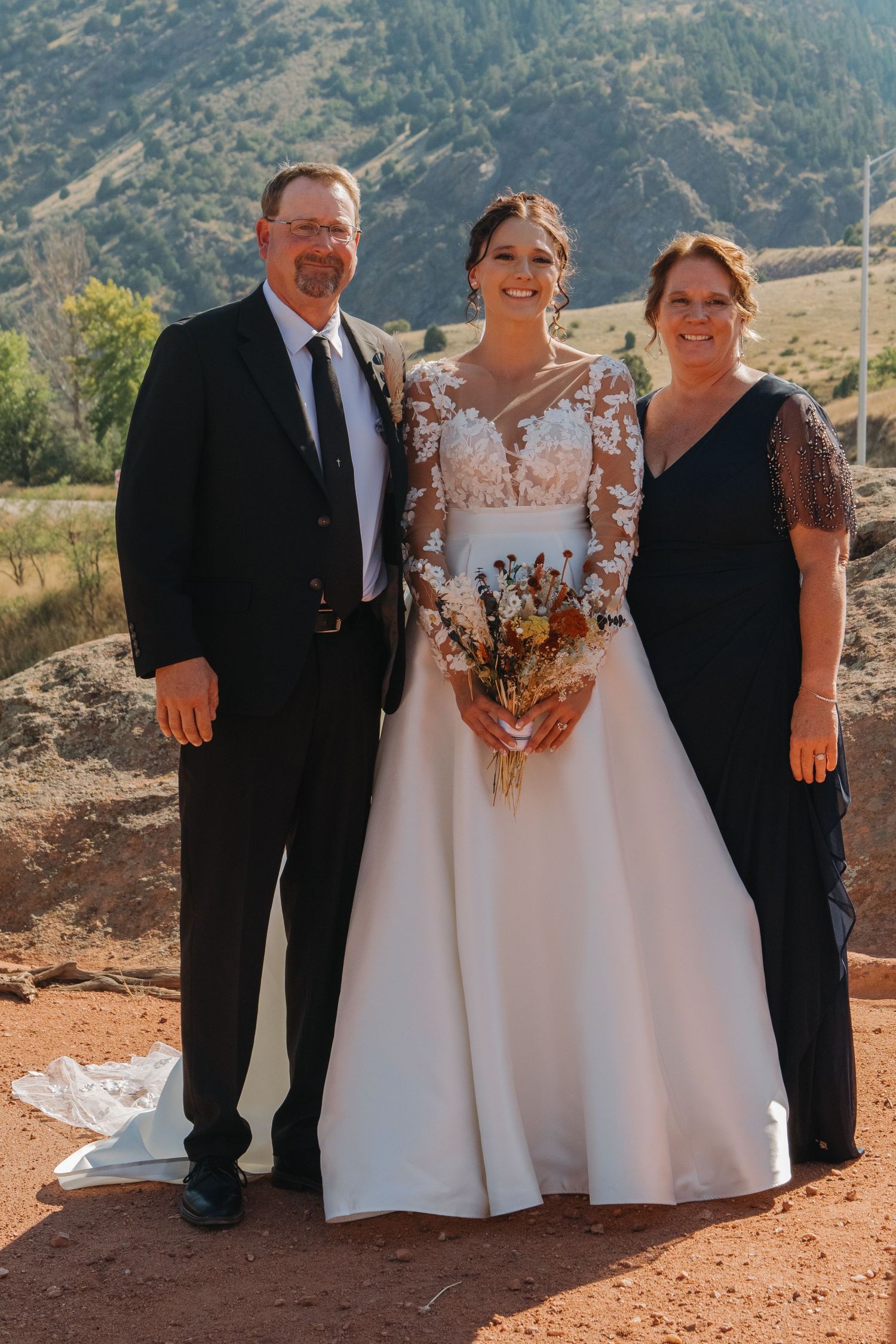 Wedding party posing for formal photos against scenic mountain backdrop.
