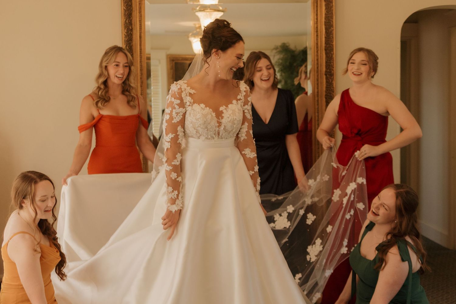 Wedding party reactions as bride reveals her dress in an elegant indoor setting.