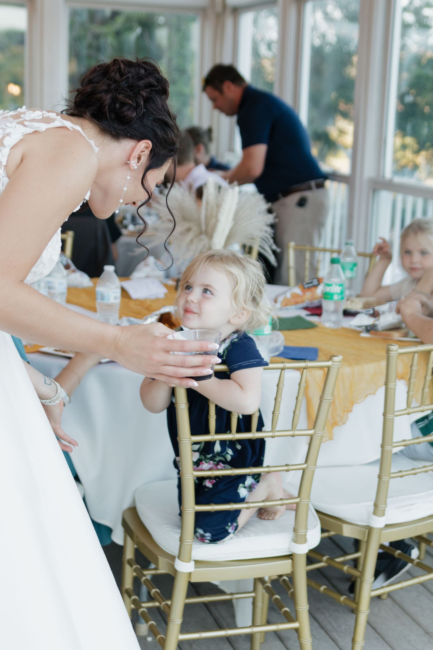 Guests seated at tables with gold chairs during an elegant indoor reception.