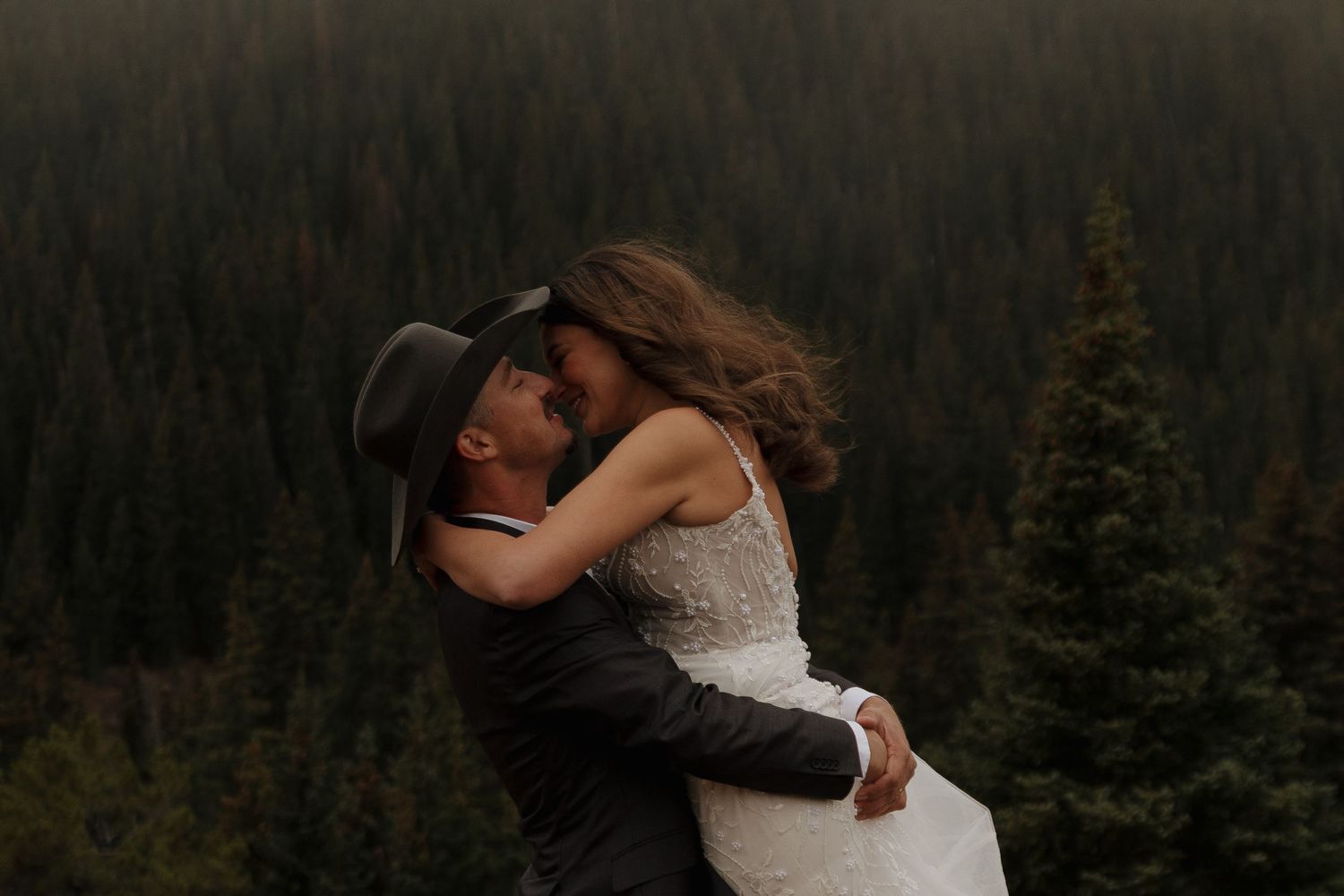 Romantic embrace against a backdrop of mountain forests at dusk.