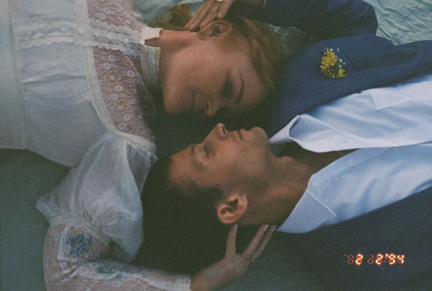 Bride and groom lying down together smiling at each other on their wedding day.
