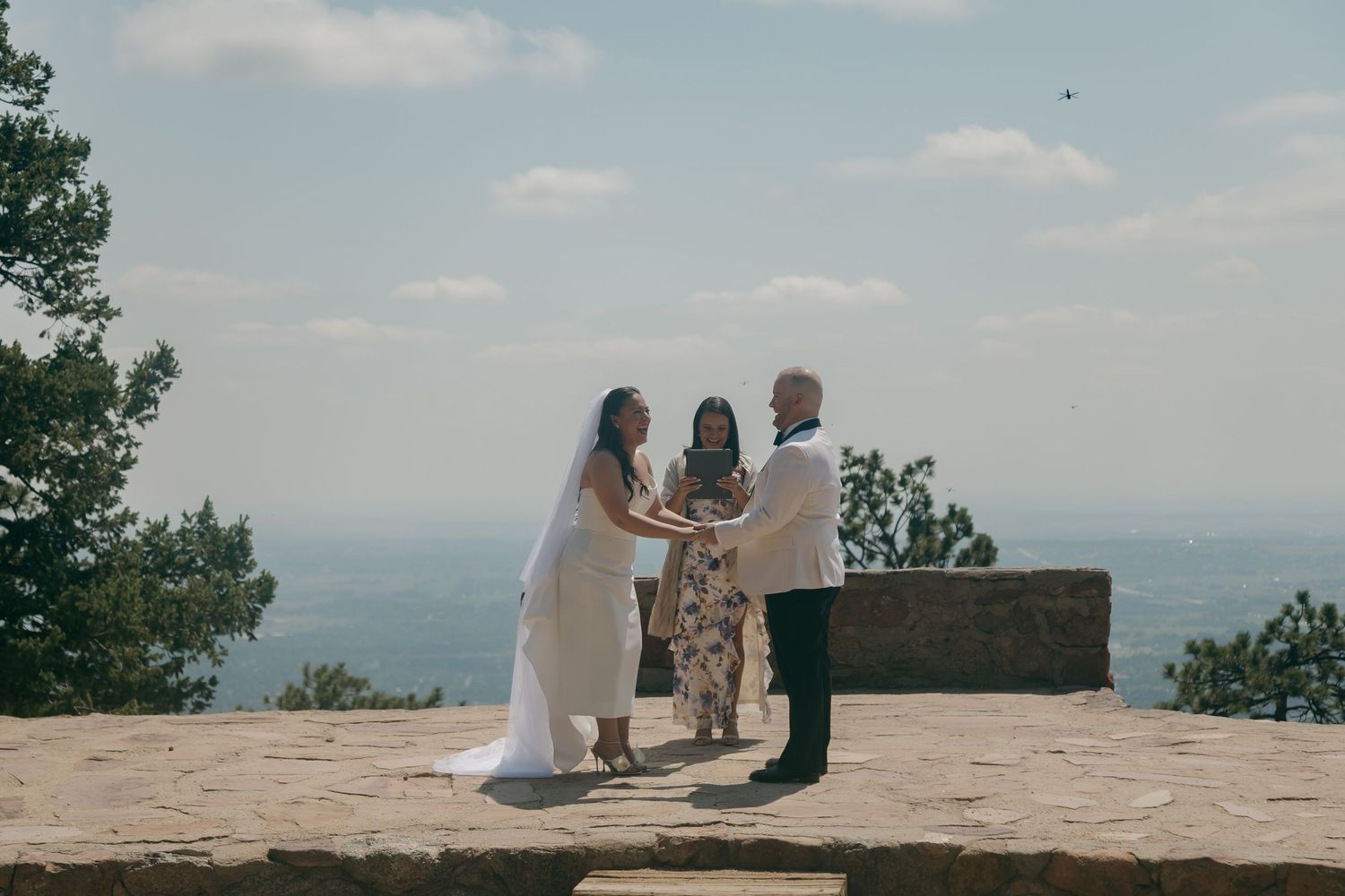 Couple exchanges vows at an outdoor mountain overlook wedding ceremony with an officiant on a sunny day.