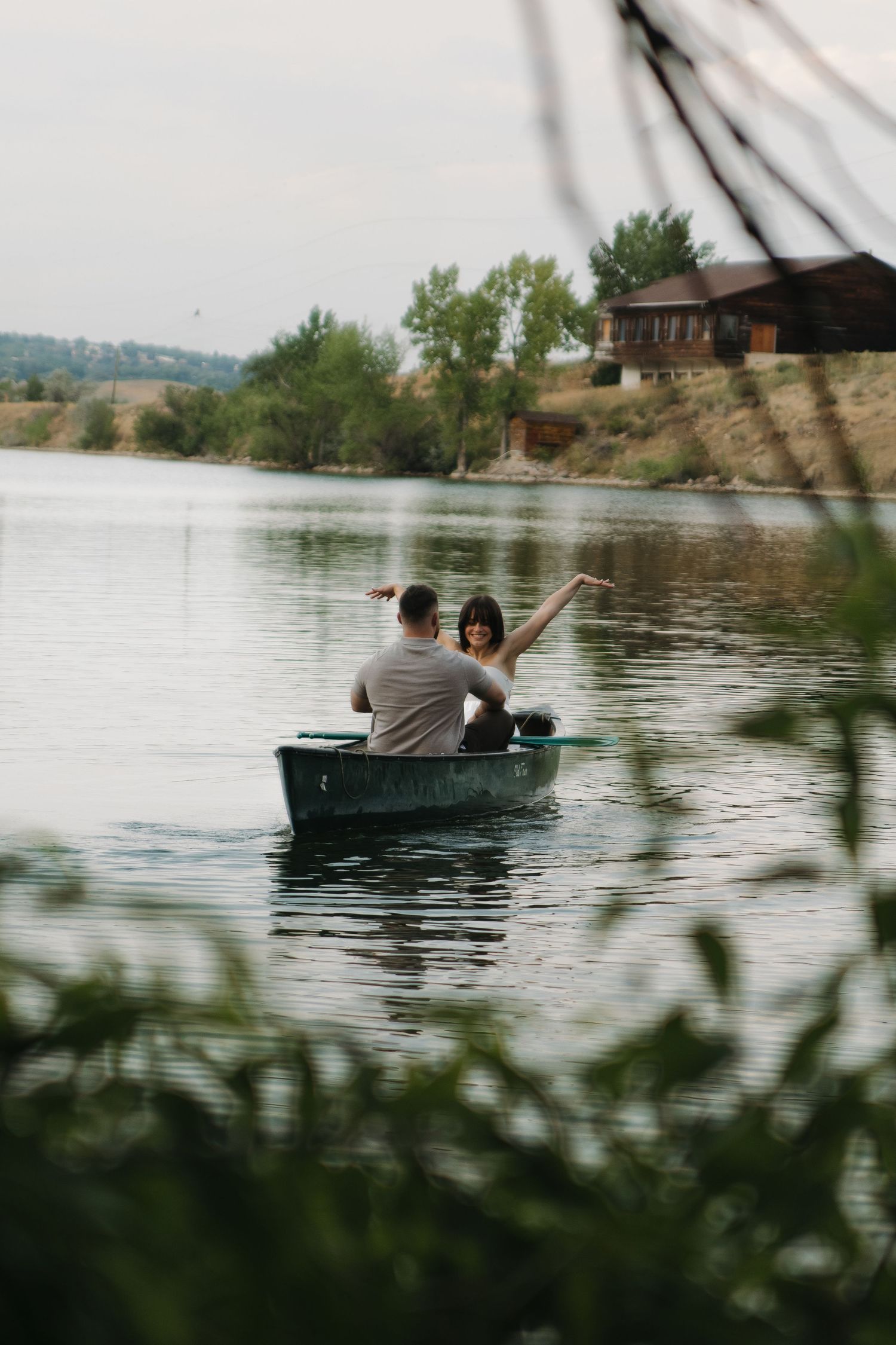 A couple spending a peaceful afternoon rowing in a small boat on a serene lake surrounded by nature.
