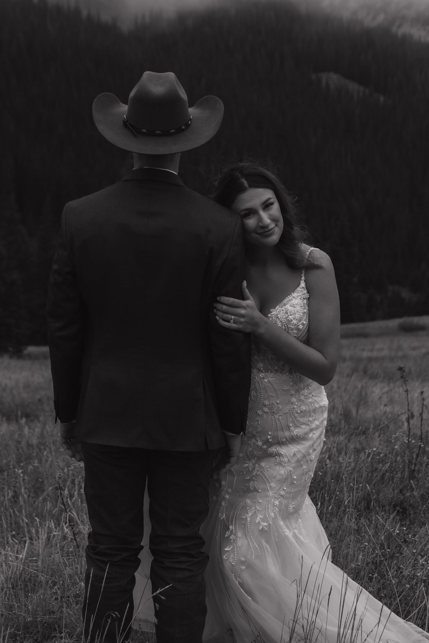 Black and white wedding photos capture intimate moments between newlyweds in a mountain meadow.