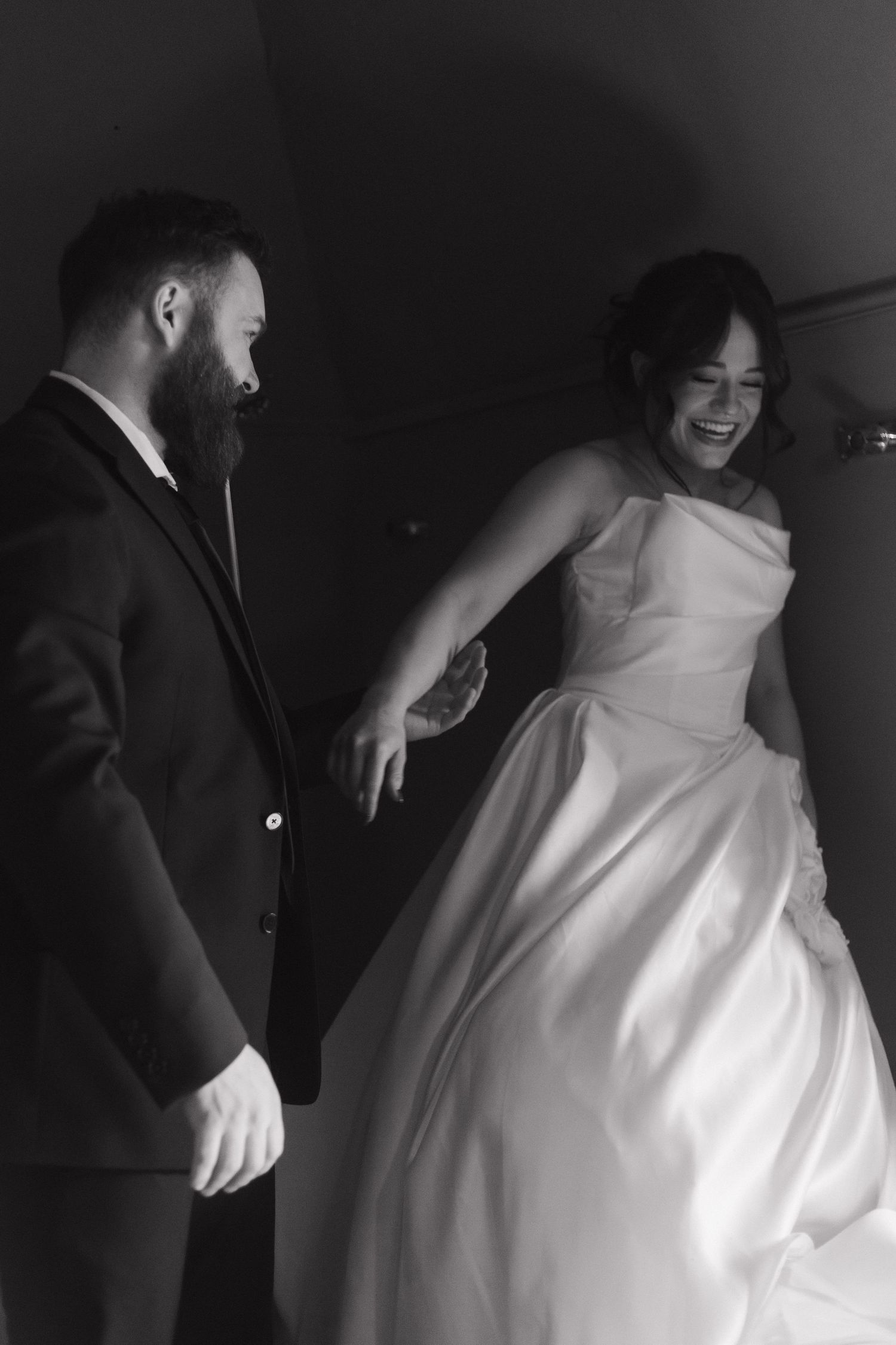Elegant white wedding dress captured in motion against dark background.