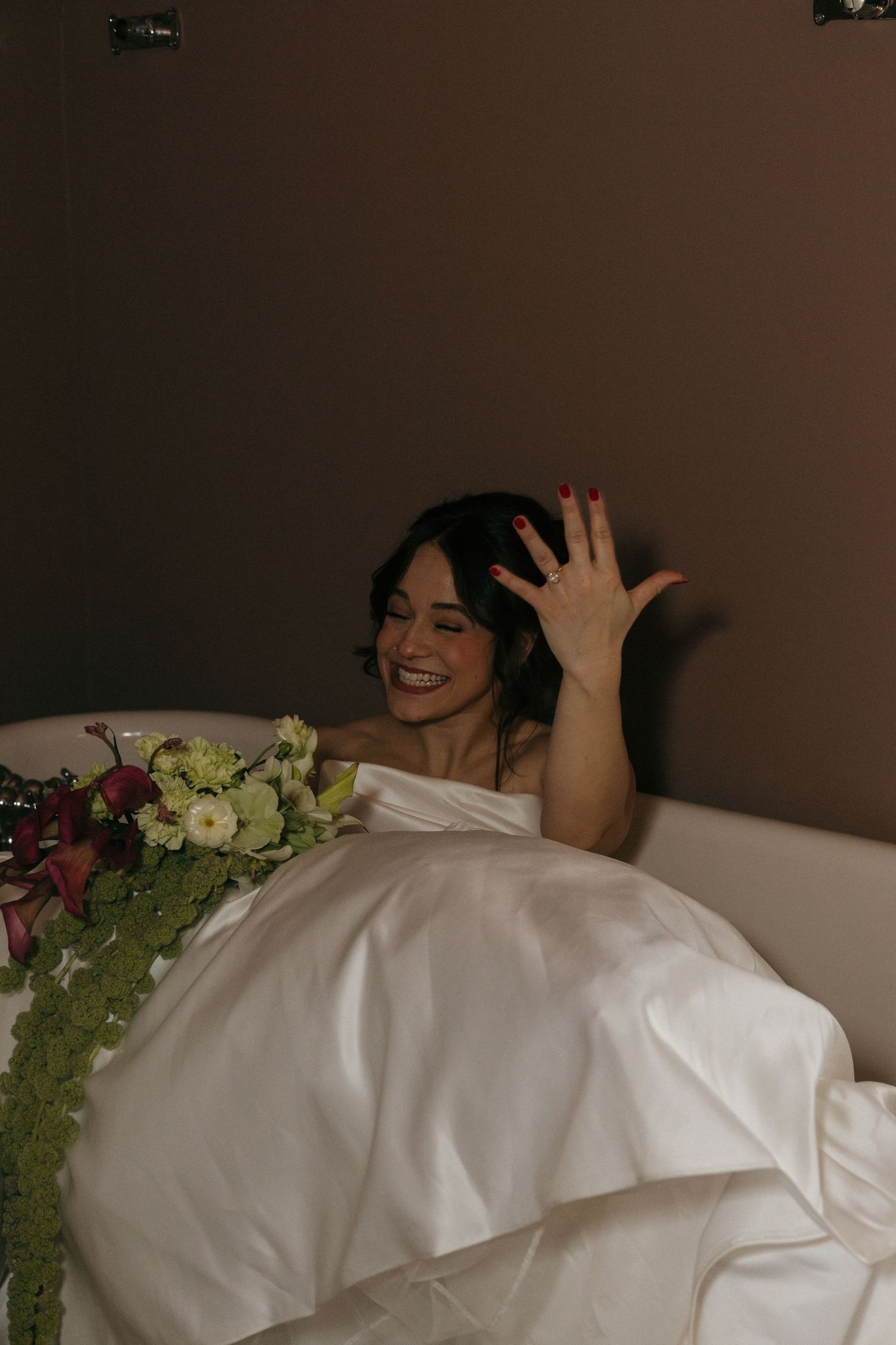 A playful wedding scene showing laughter and joy while resting on a white couch.