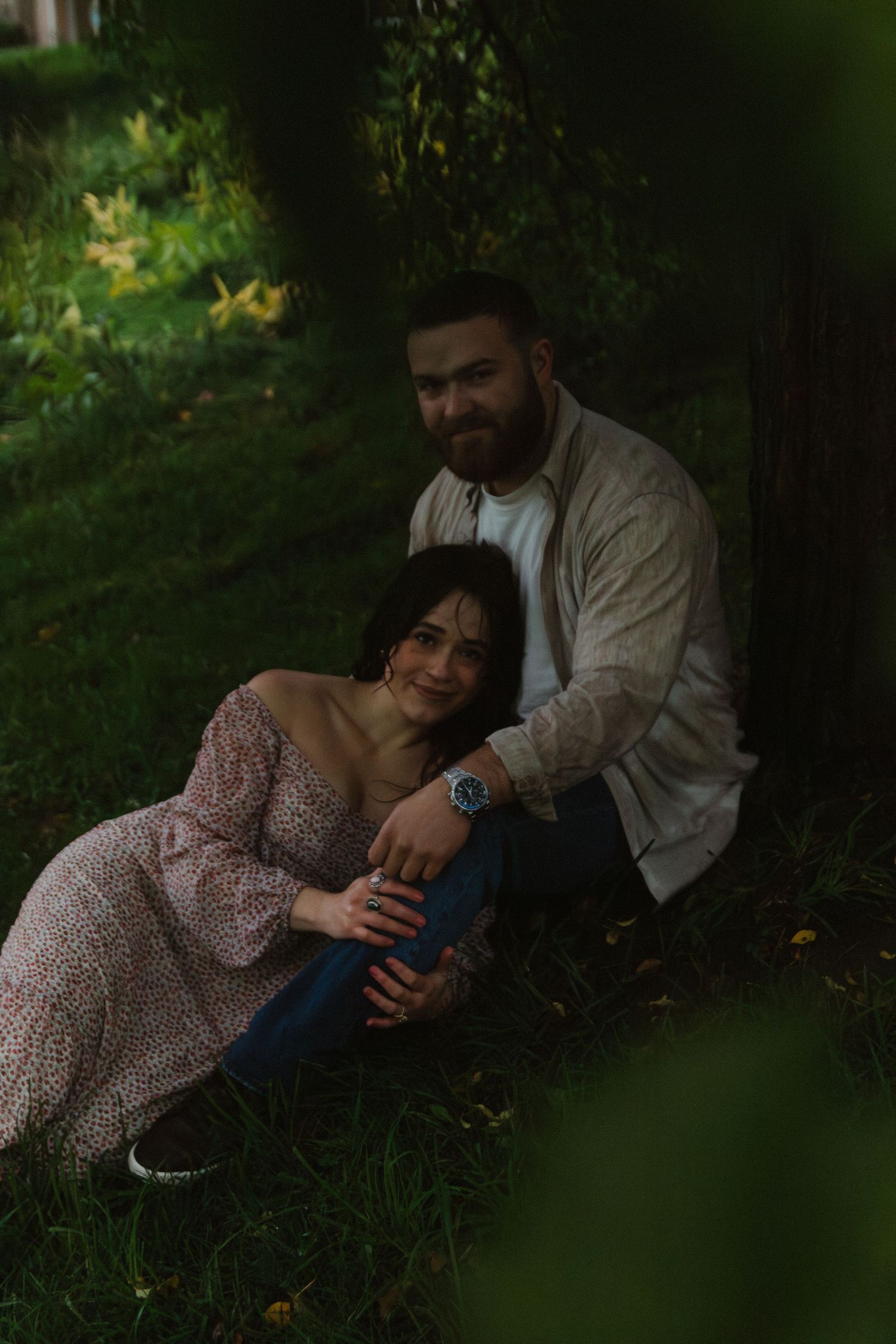 Couple relaxing together on grass in a peaceful outdoor setting with natural lighting.
