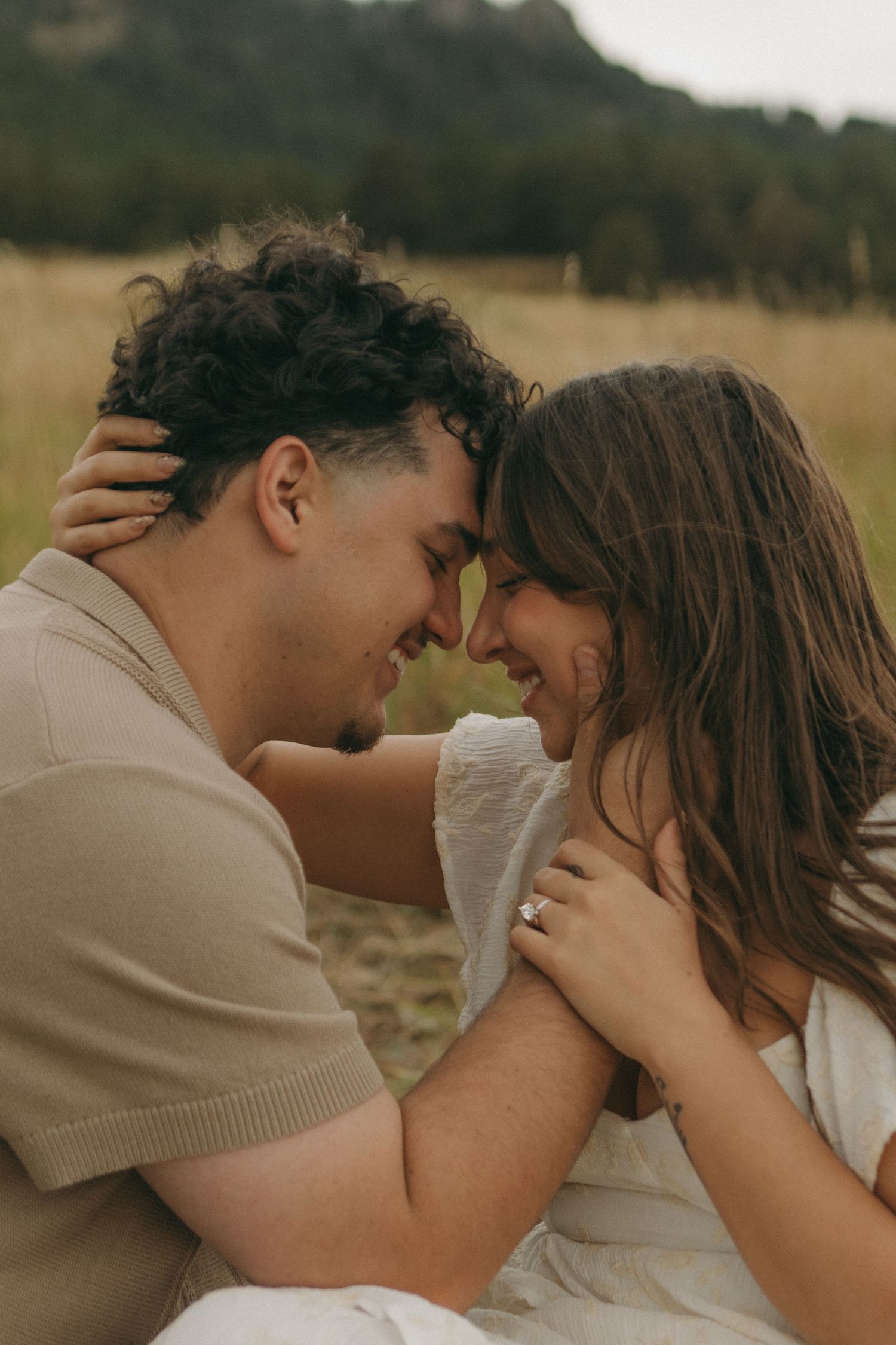 Smiling couple touching foreheads in an intimate moment during a romantic outdoor engagement photo session.