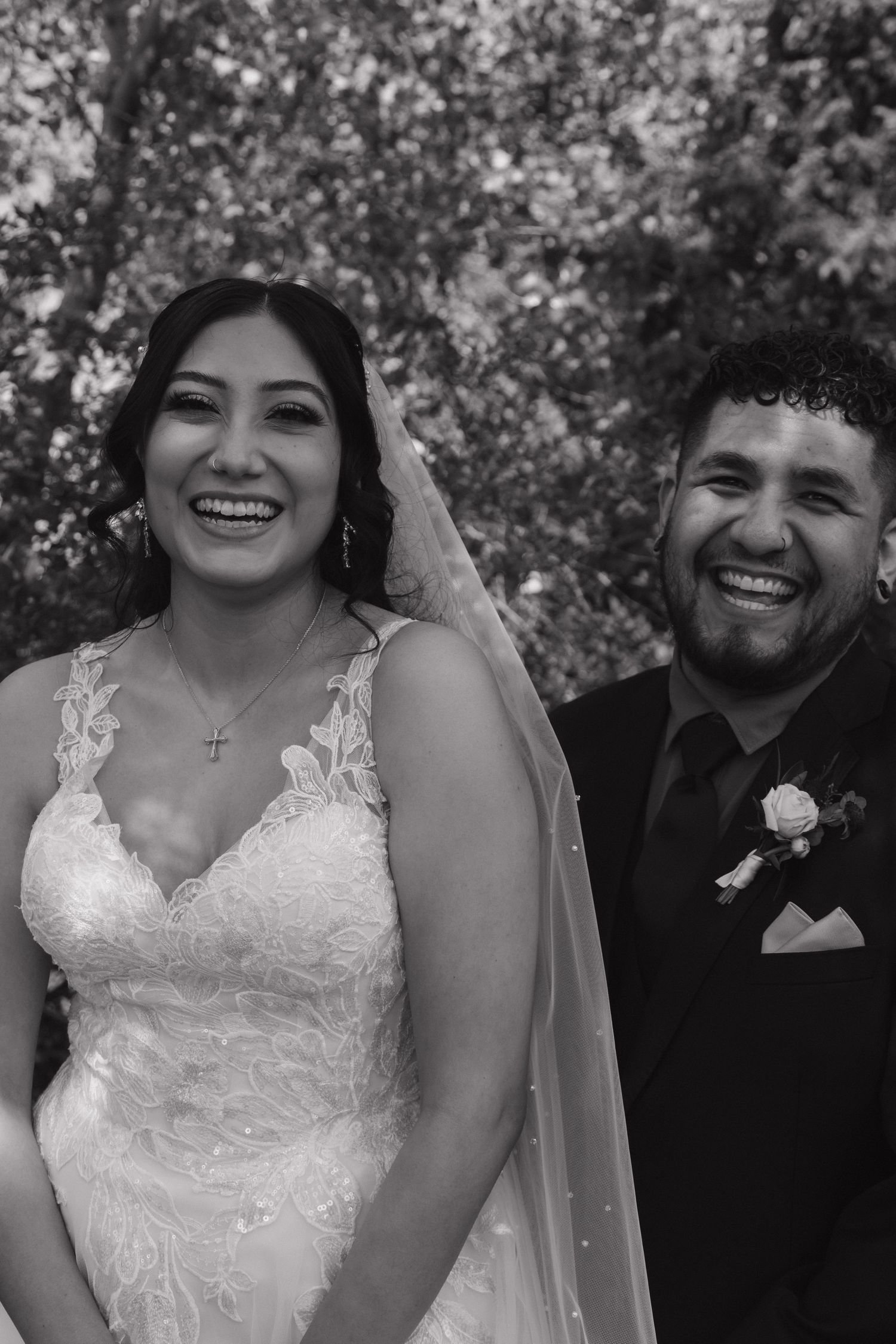 Black and white portrait of smiling bride and groom laughing joyfully together on their wedding day.