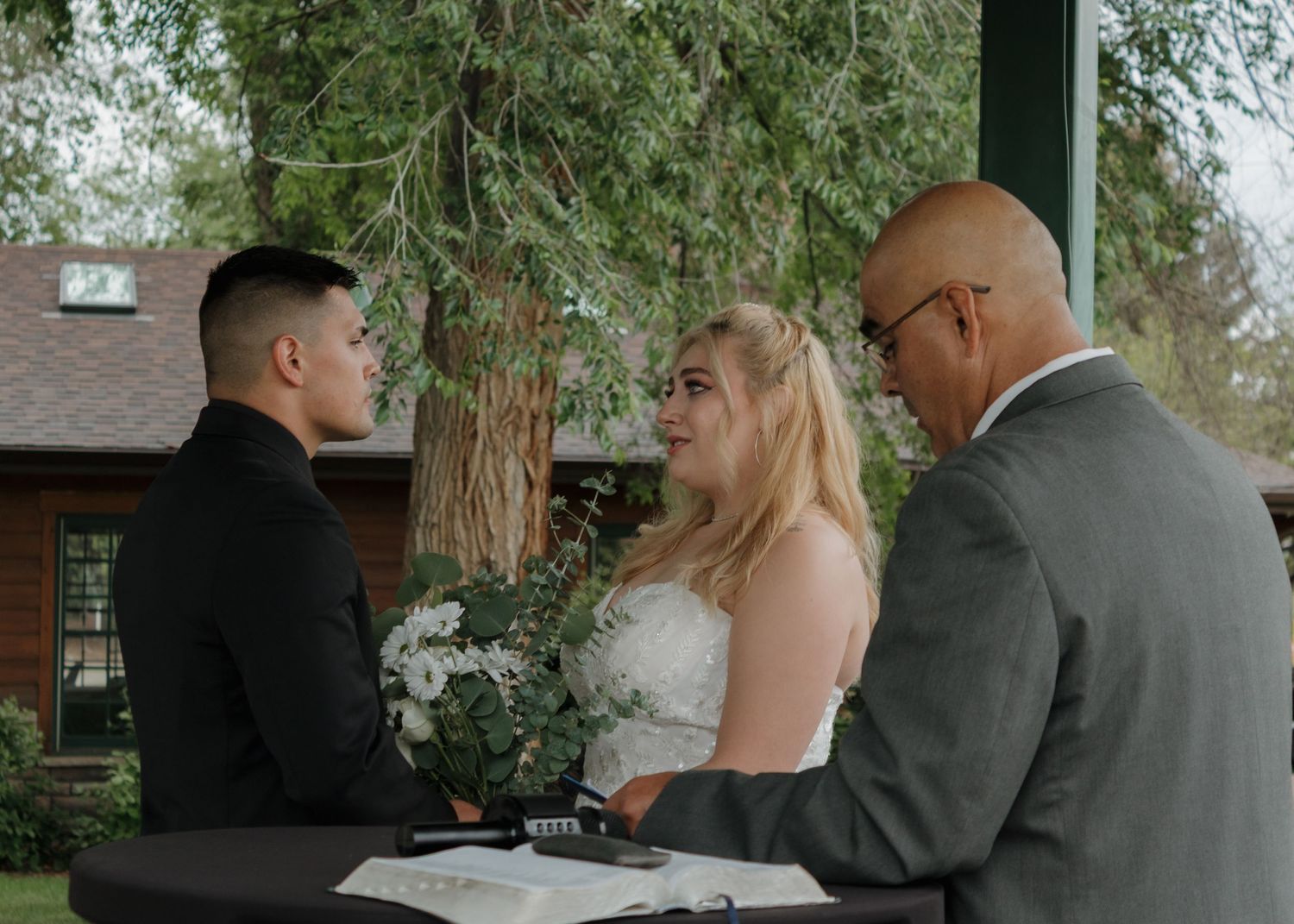 Close-up shot of a wedding ring exchange between two hands during an outdoor ceremony.
