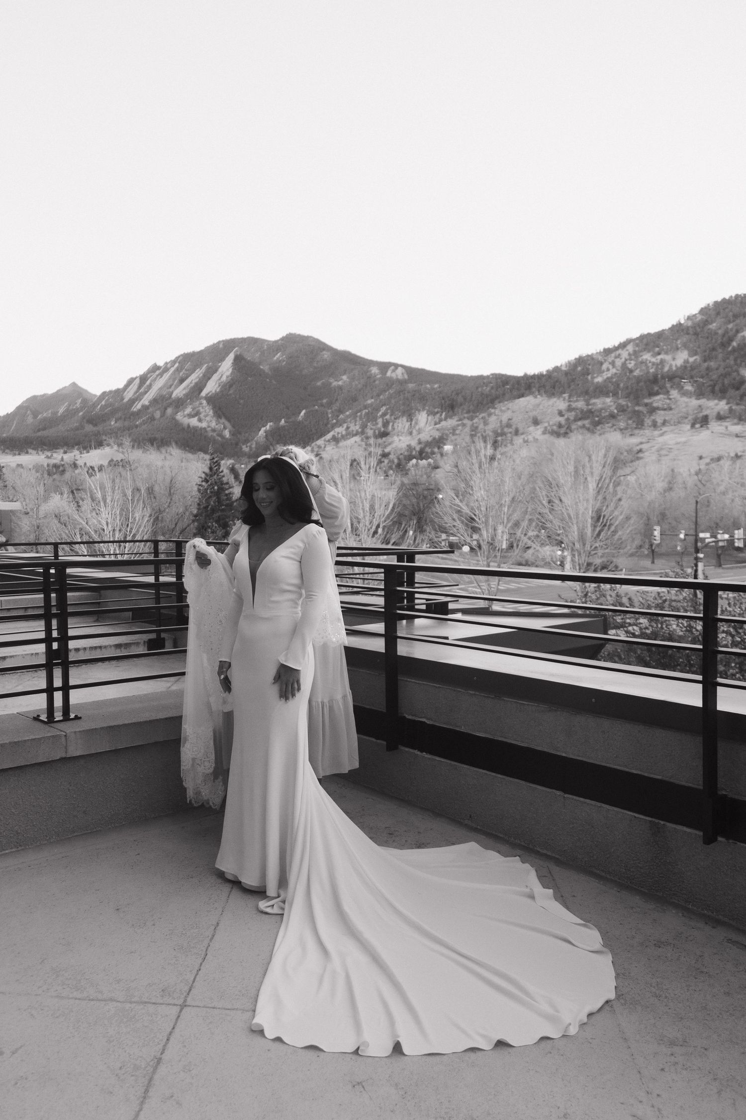 Bride in stunning long-sleeve wedding gown poses on mountain-view balcony in Boulder, Colorado.