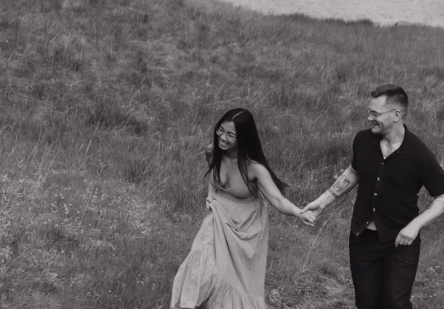 Black and white photo series captures playful moments between two people on a hillside.